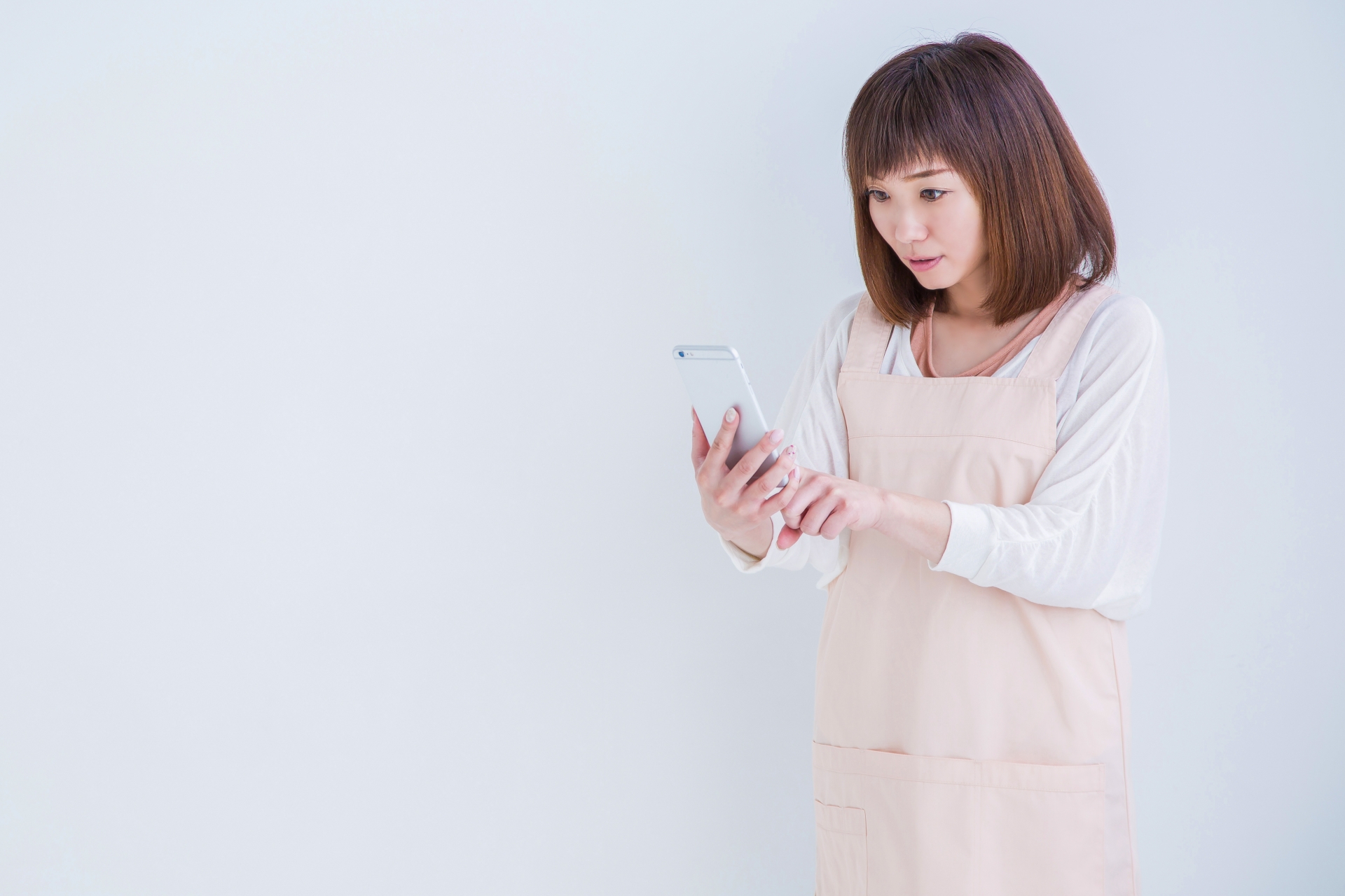 電話を持ってびっくりするエプロン姿の女性
