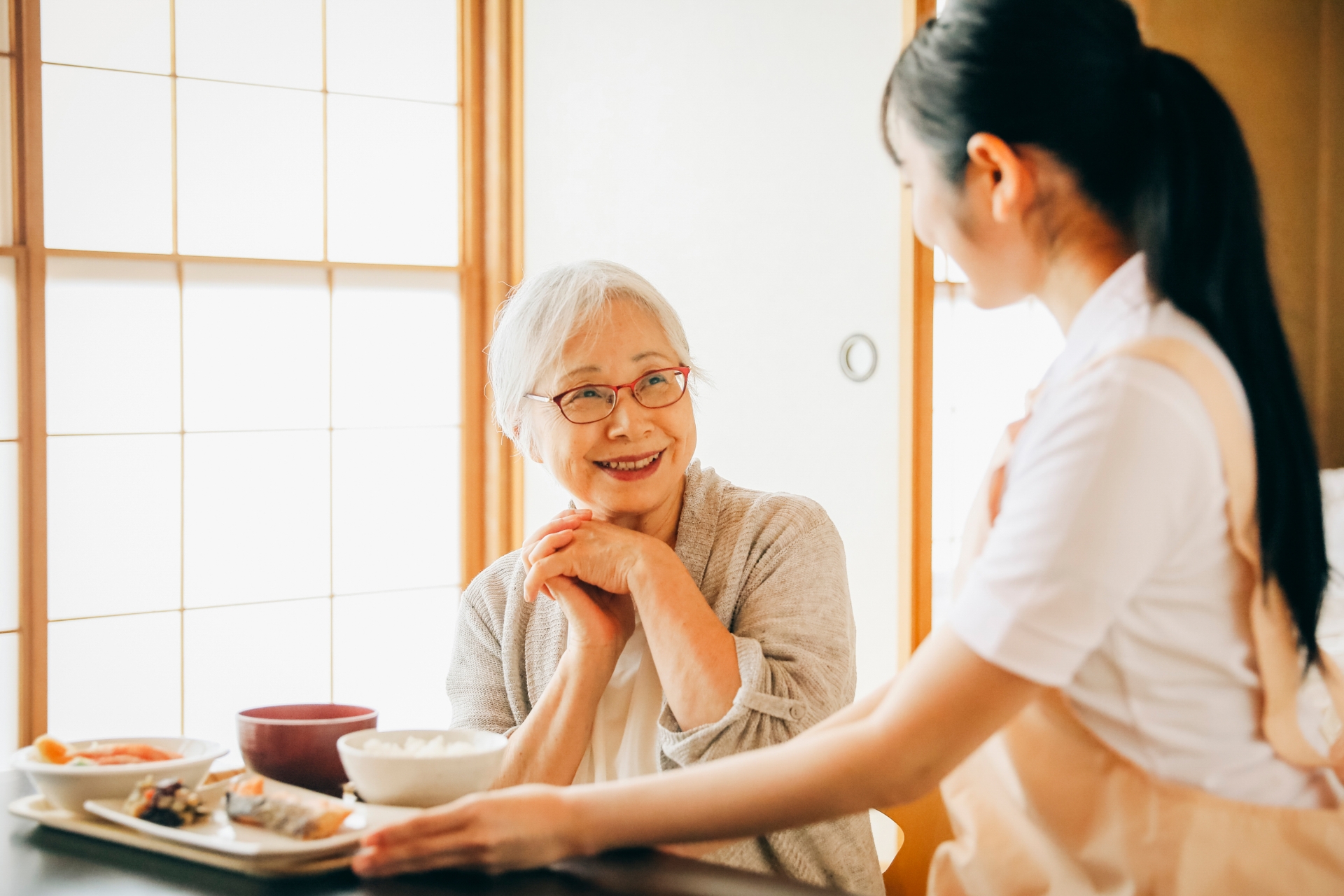 食事をする高齢者女性と女性スタッフ