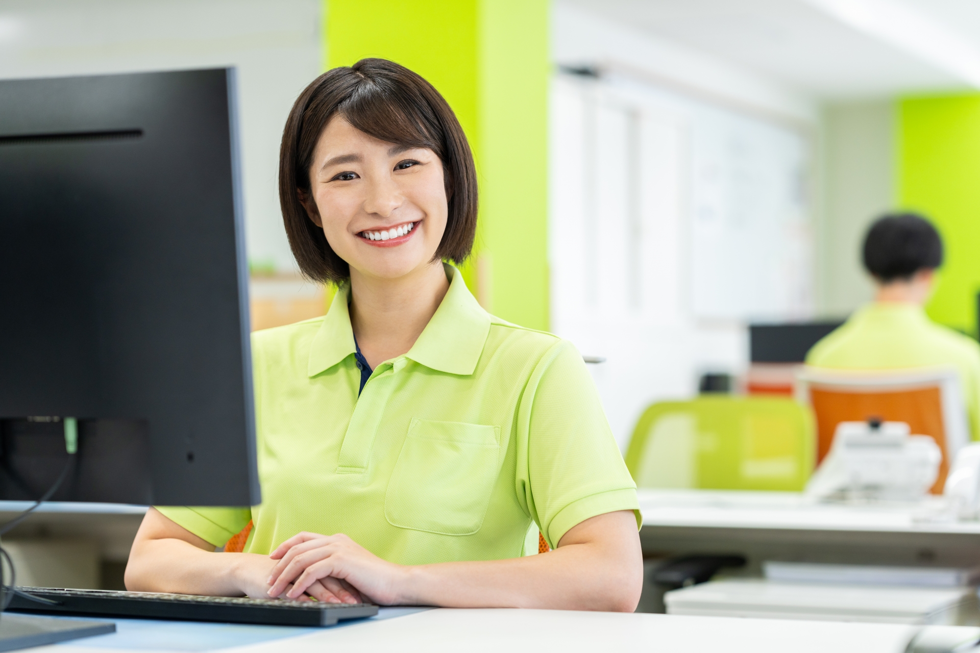 パソコンの前に座る笑顔の介護士