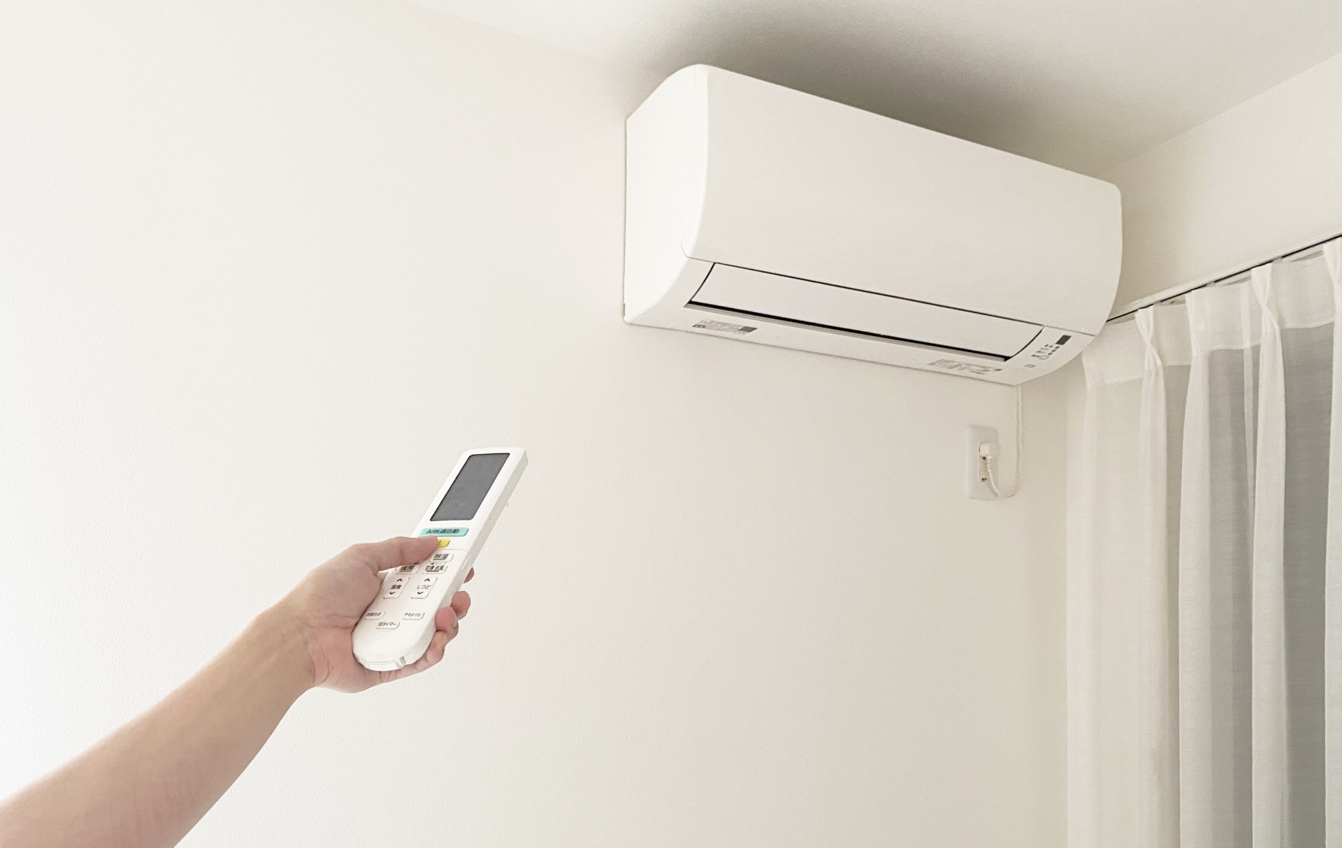 エアコンとリモコンを操作する手