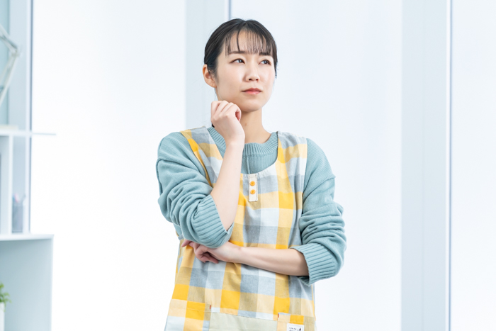 悩むエプロンをつけた女性