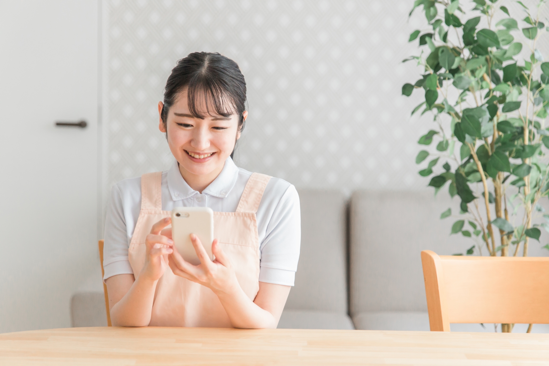 スマホを使うエプロン姿の女性