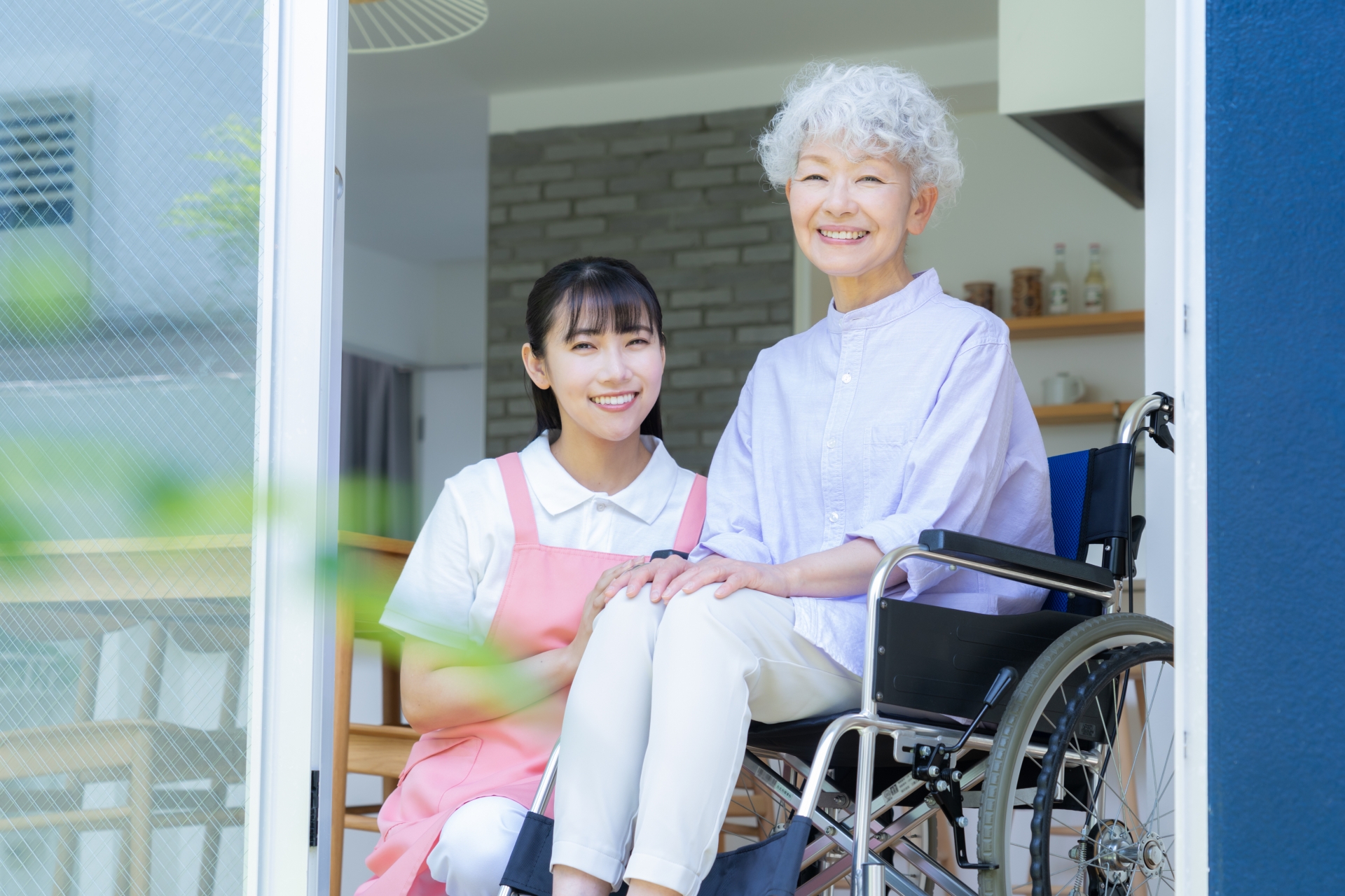 窓際でシニア女性を介護をする介護士の女性