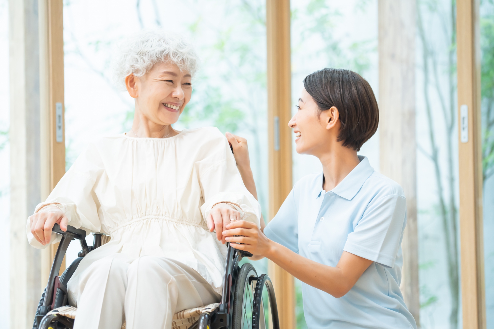 車椅子の女性と話をする介護士