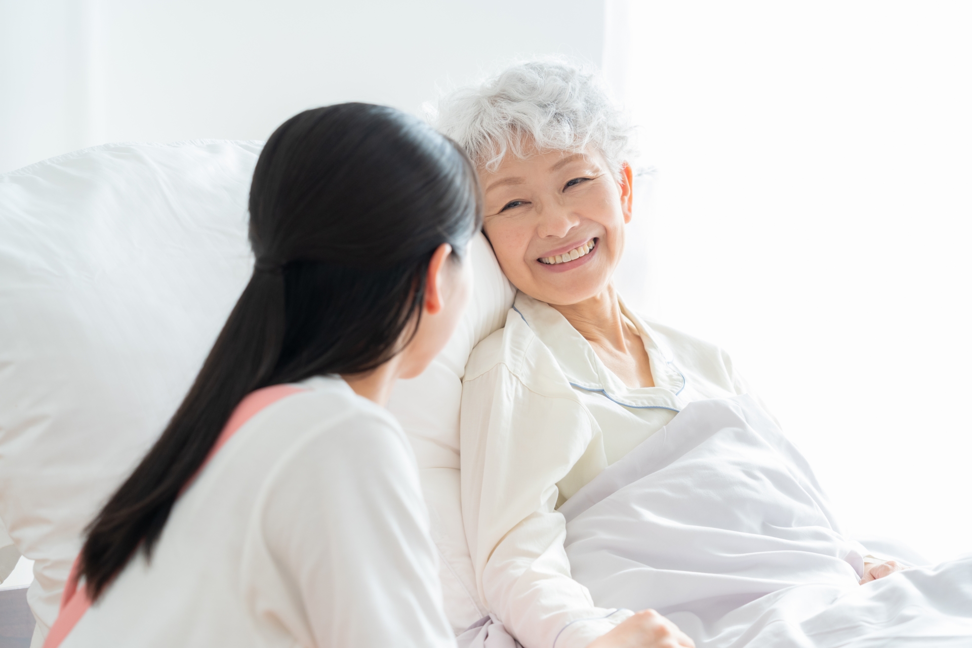 ベッドの利用者と話をする介護士