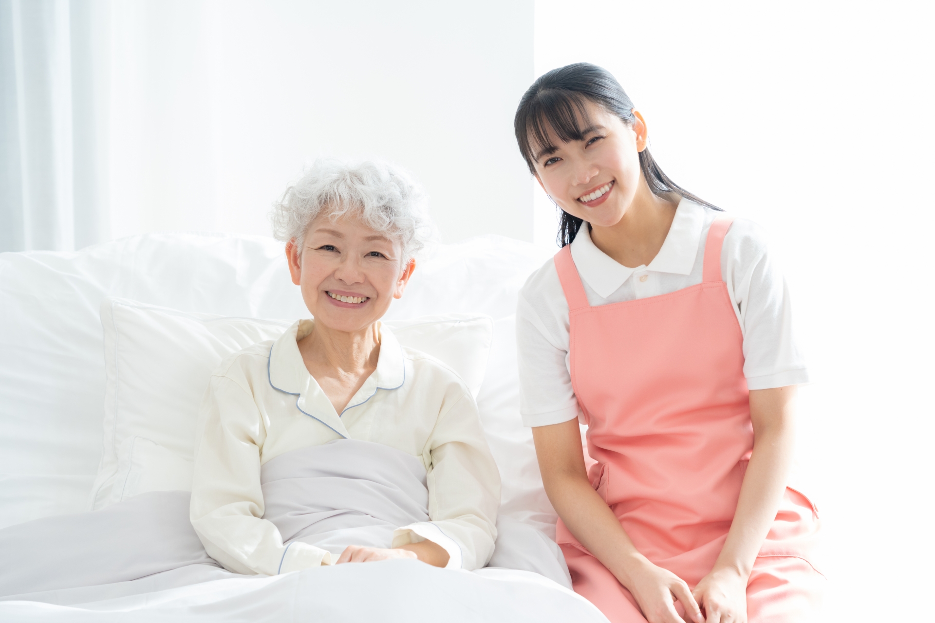寝ているシニア女性を介護をする介護士