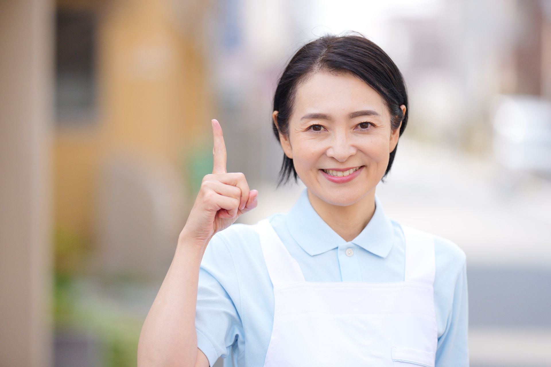 屋外で人差し指を立てる女性介護士
