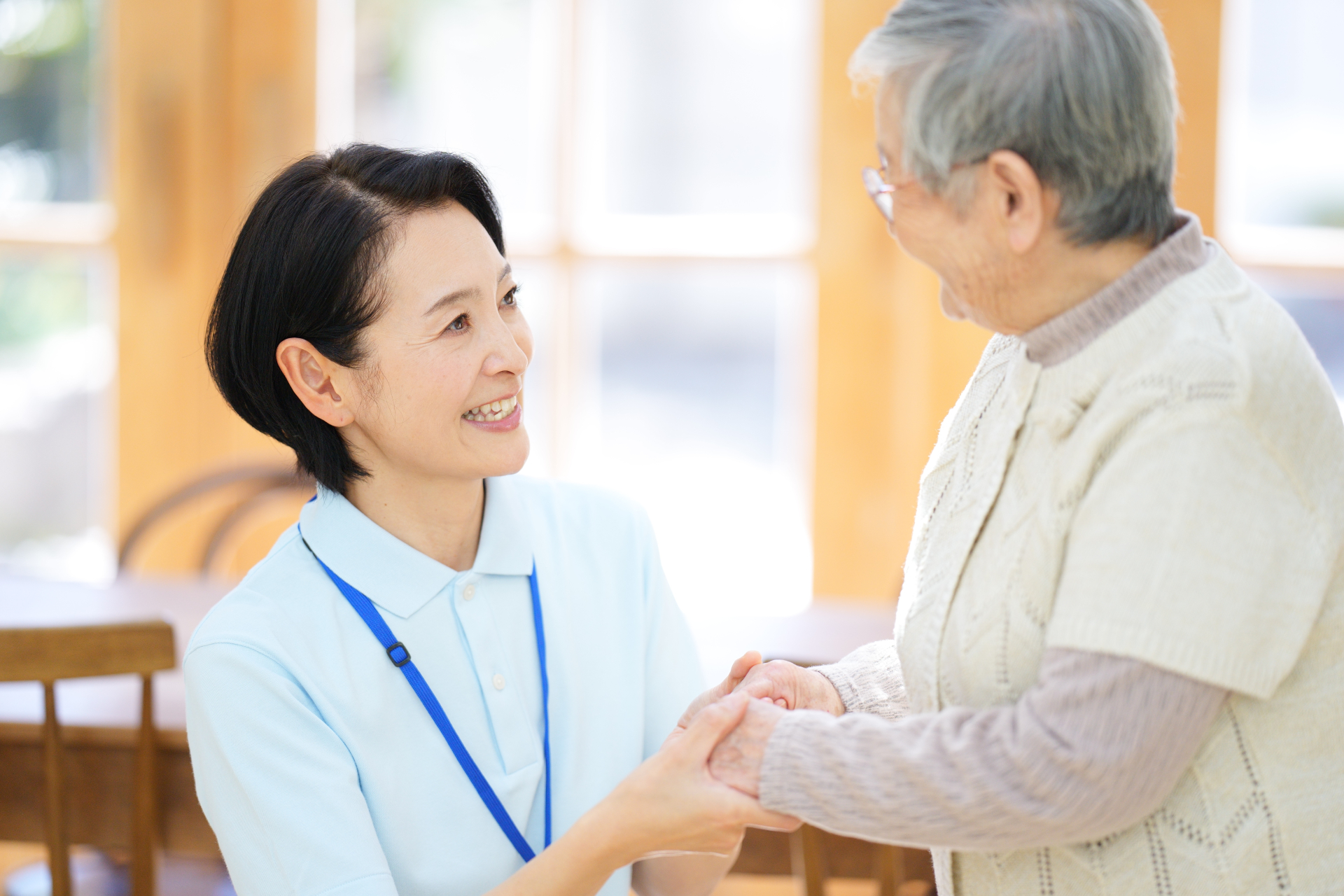 手を握り合う高齢女性と介護士