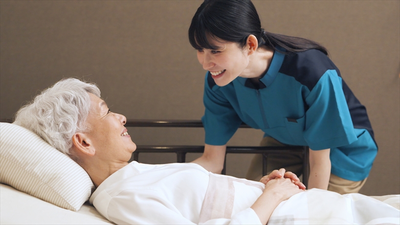 高齢者に話しかけるアジア人介護士