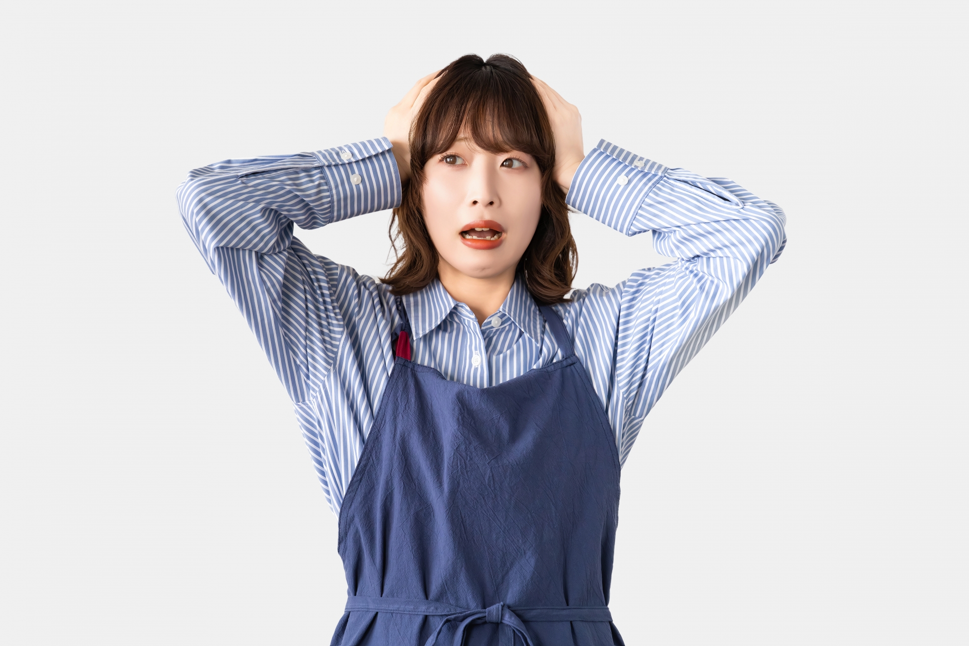 頭を抱えて悩むエプロン姿の女性