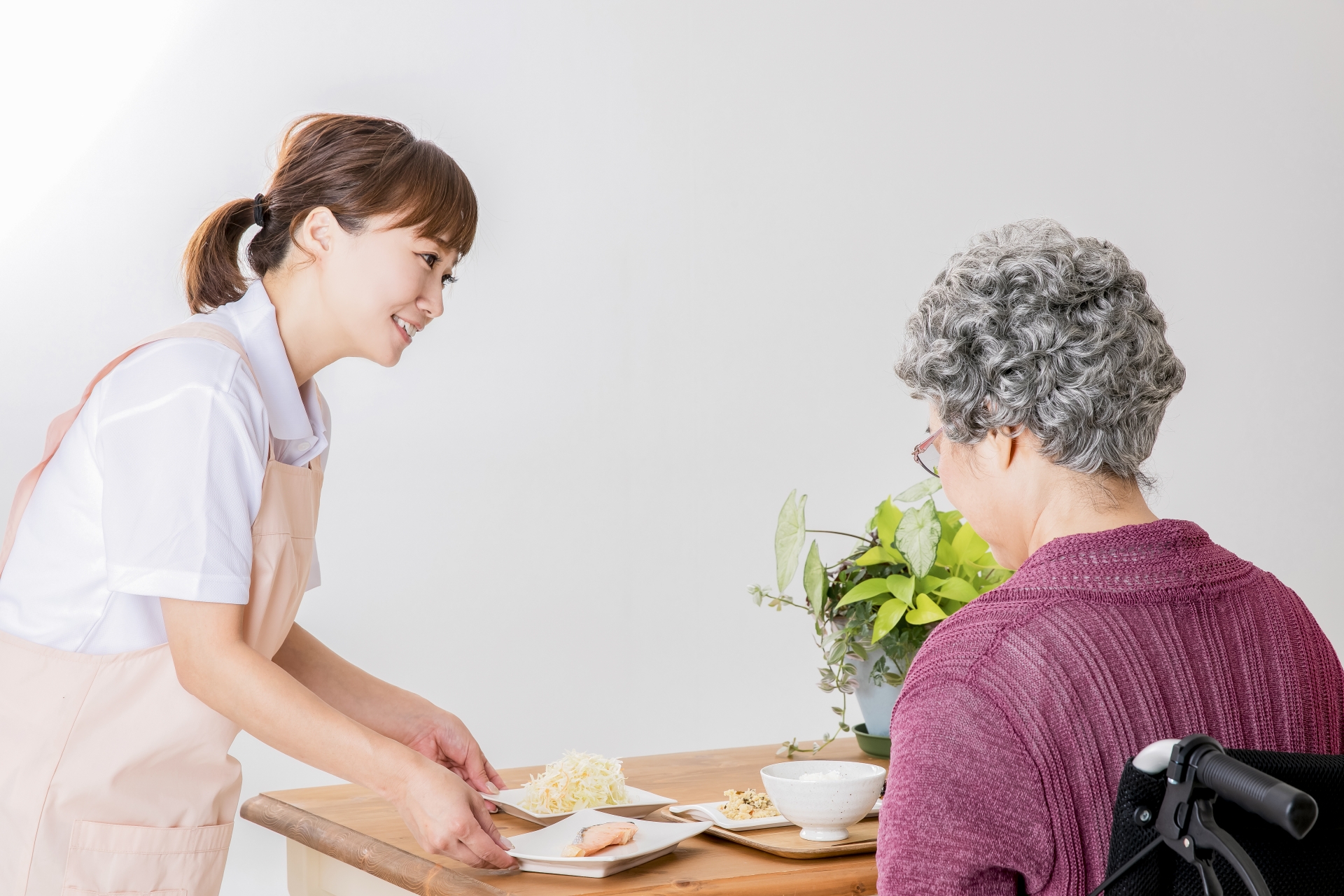 高齢者の女性と食事を運ぶ介護士