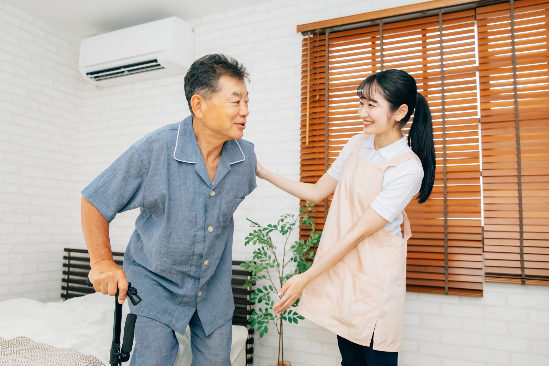 杖を使う高齢者男性と女性スタッフ