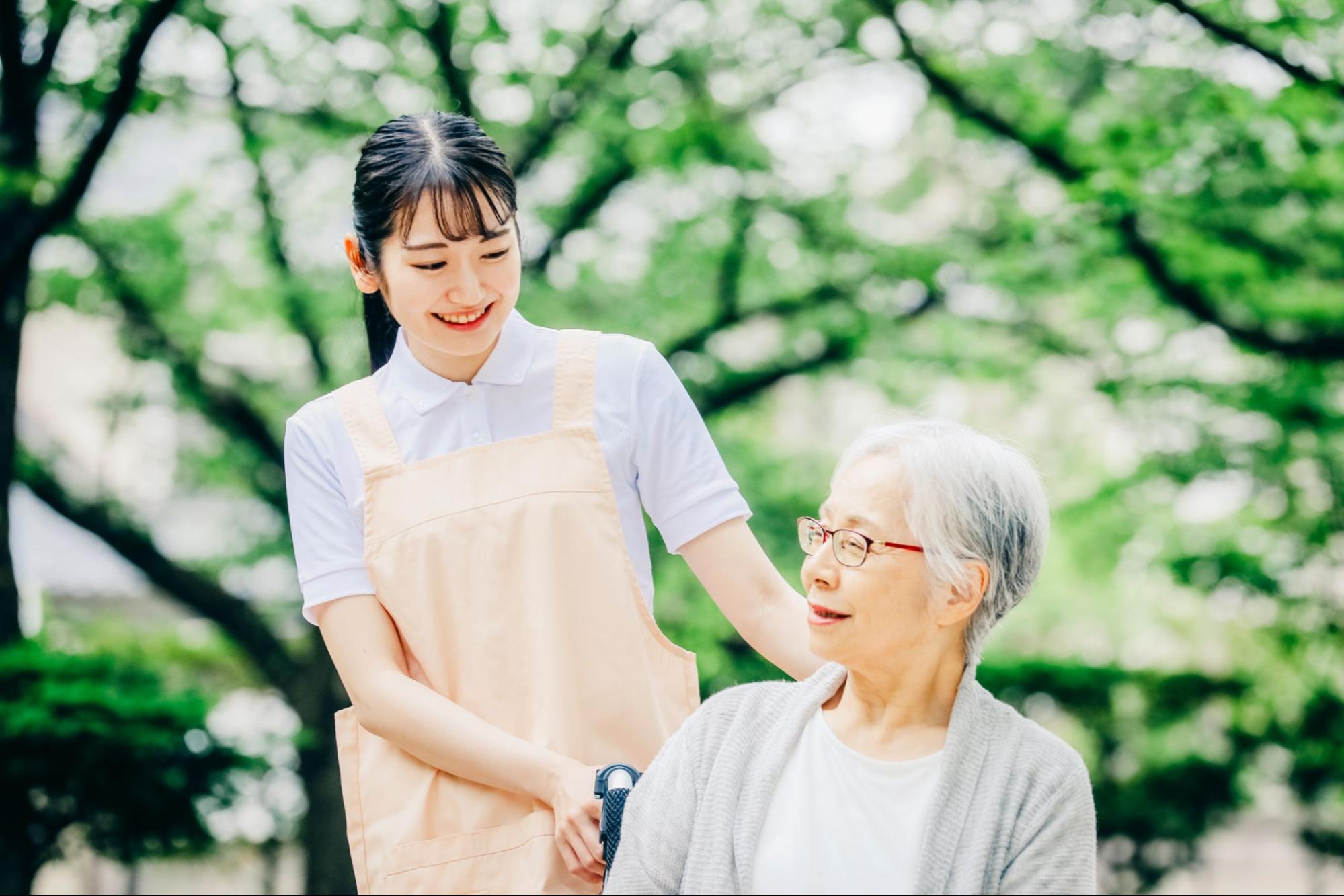 車椅子に乗った高齢者女性と女性スタッフ
