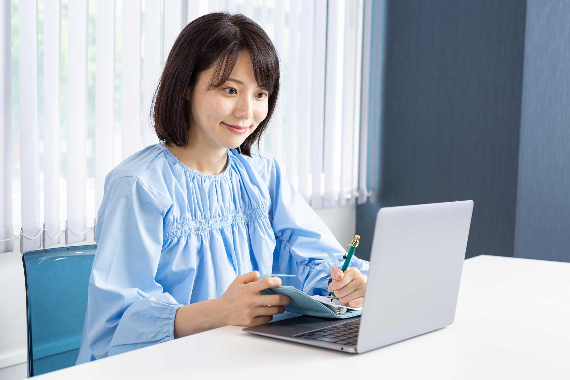 PCを操作しながらメモを取る女性