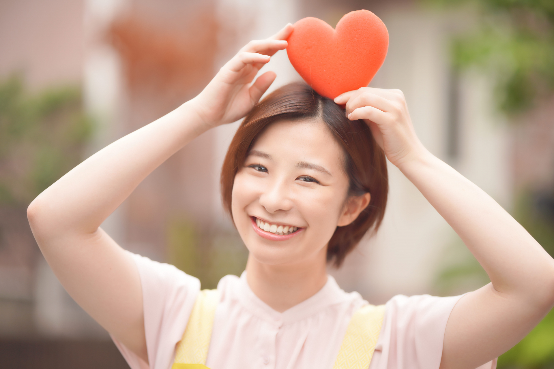 ハートの模型を頭にのせて見せるヘルパー