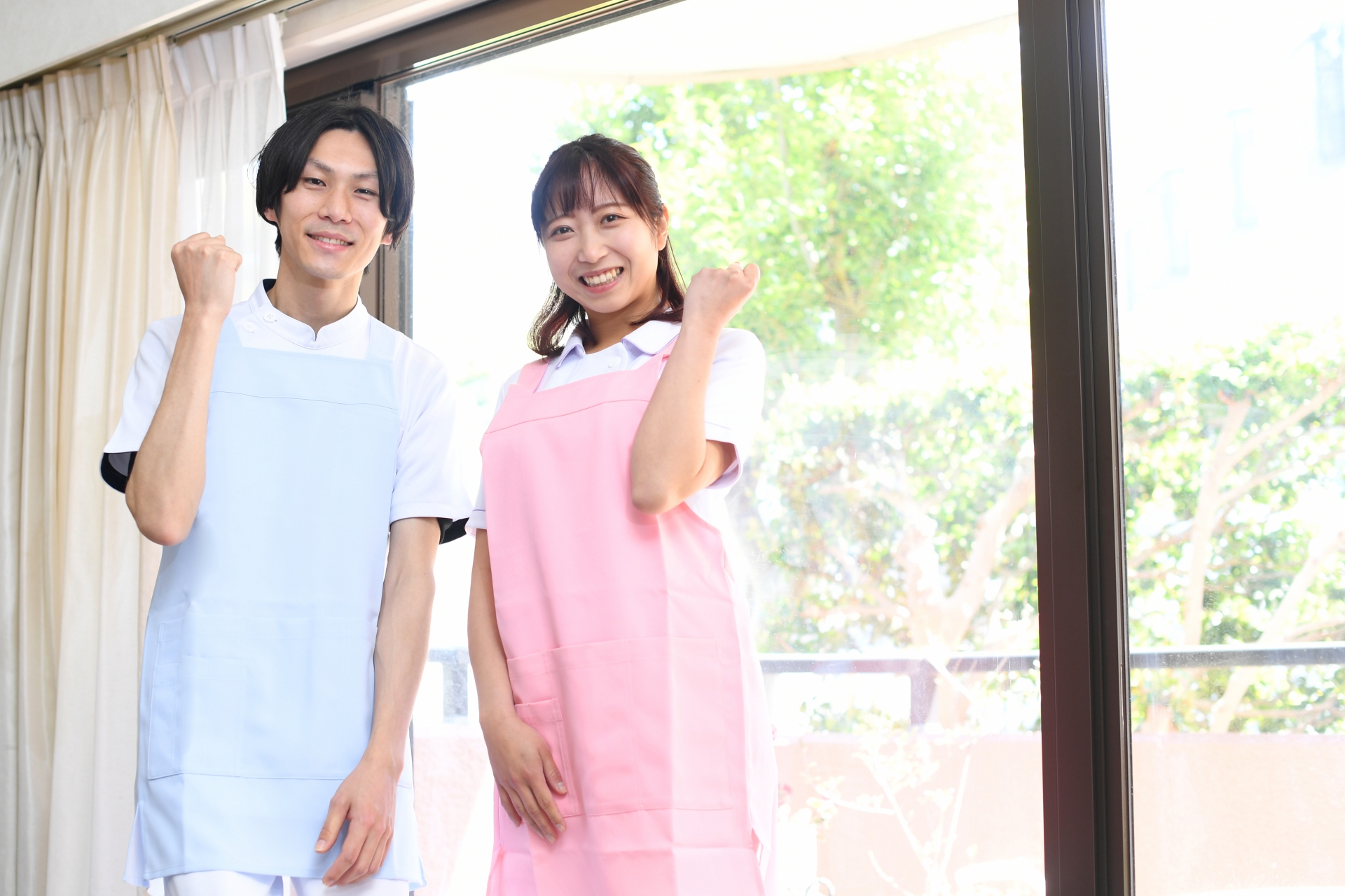ガッツポーズをするエプロン姿の男女