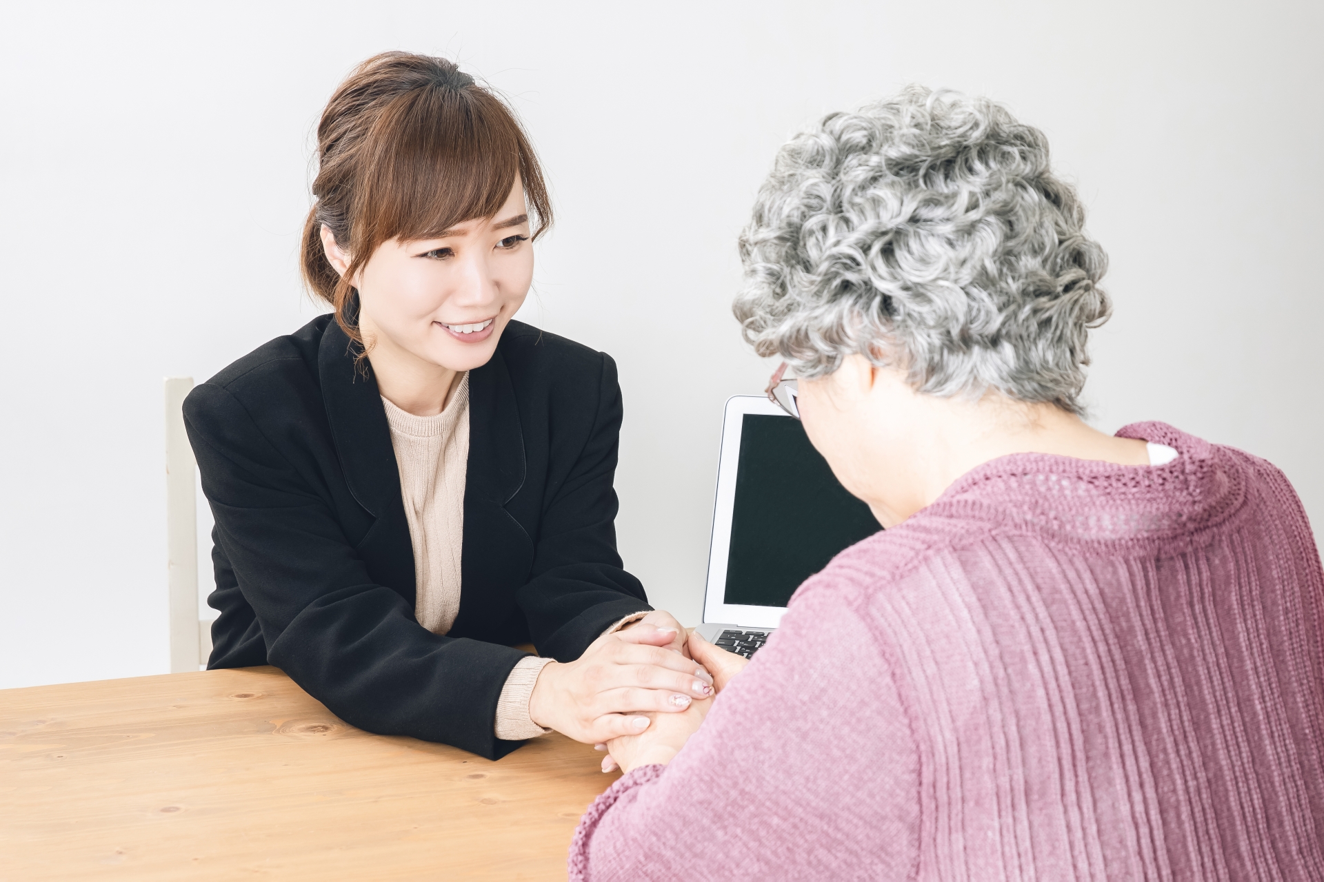 握手するスーツ姿の女性と高齢者