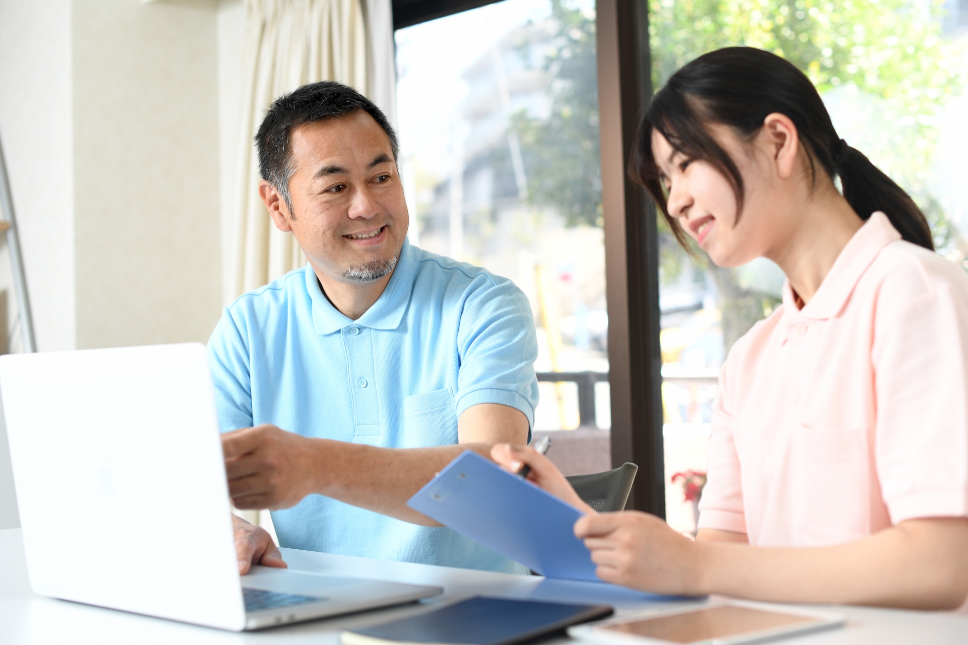 パソコンの前にいるベテラン介護士と若い介護士