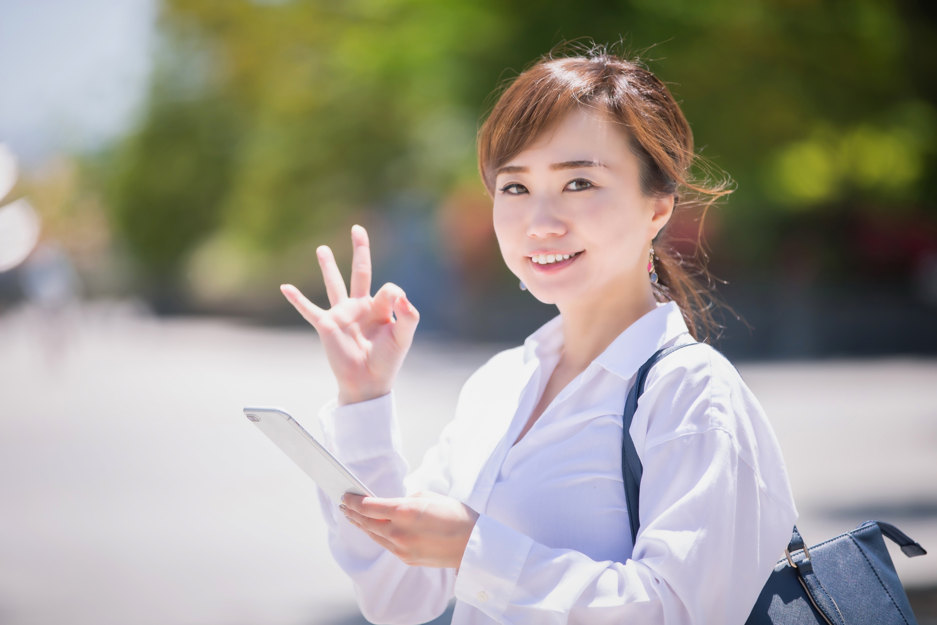 スマホを持ってOKサインする女性
