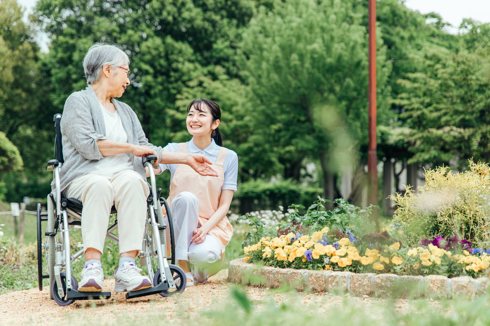車椅子に乗った高齢者女性と介護士