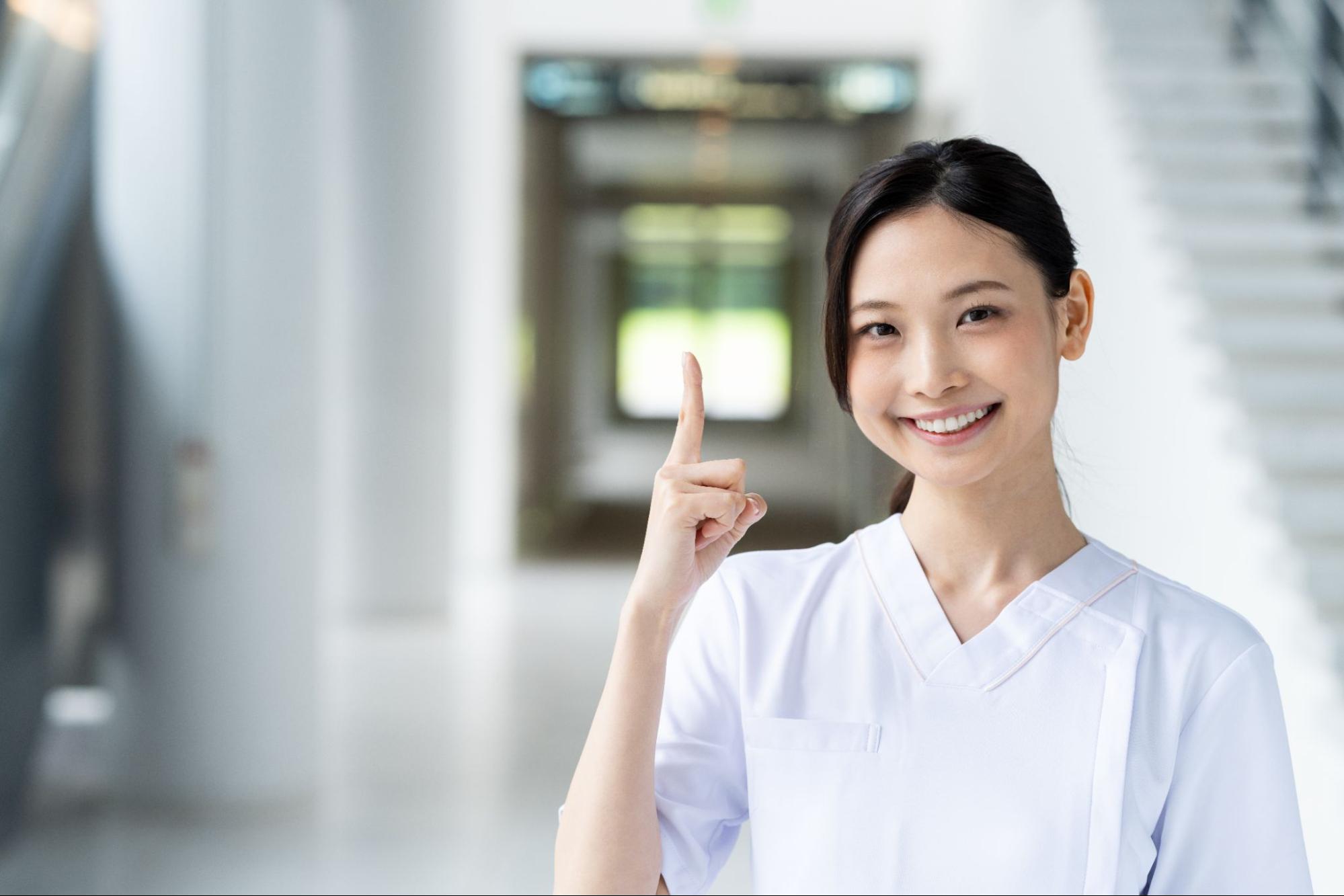 指を立てる白衣の女性