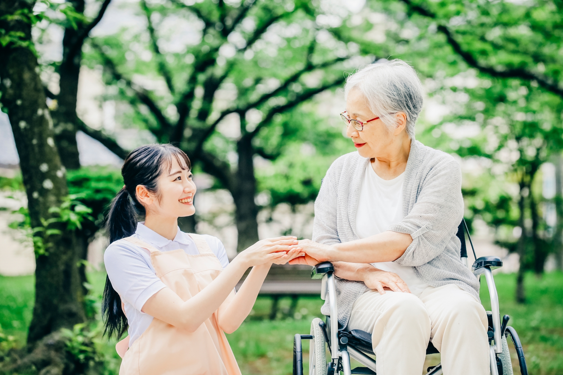 車椅子に乗った高齢者女性と女性スタッフ(手)