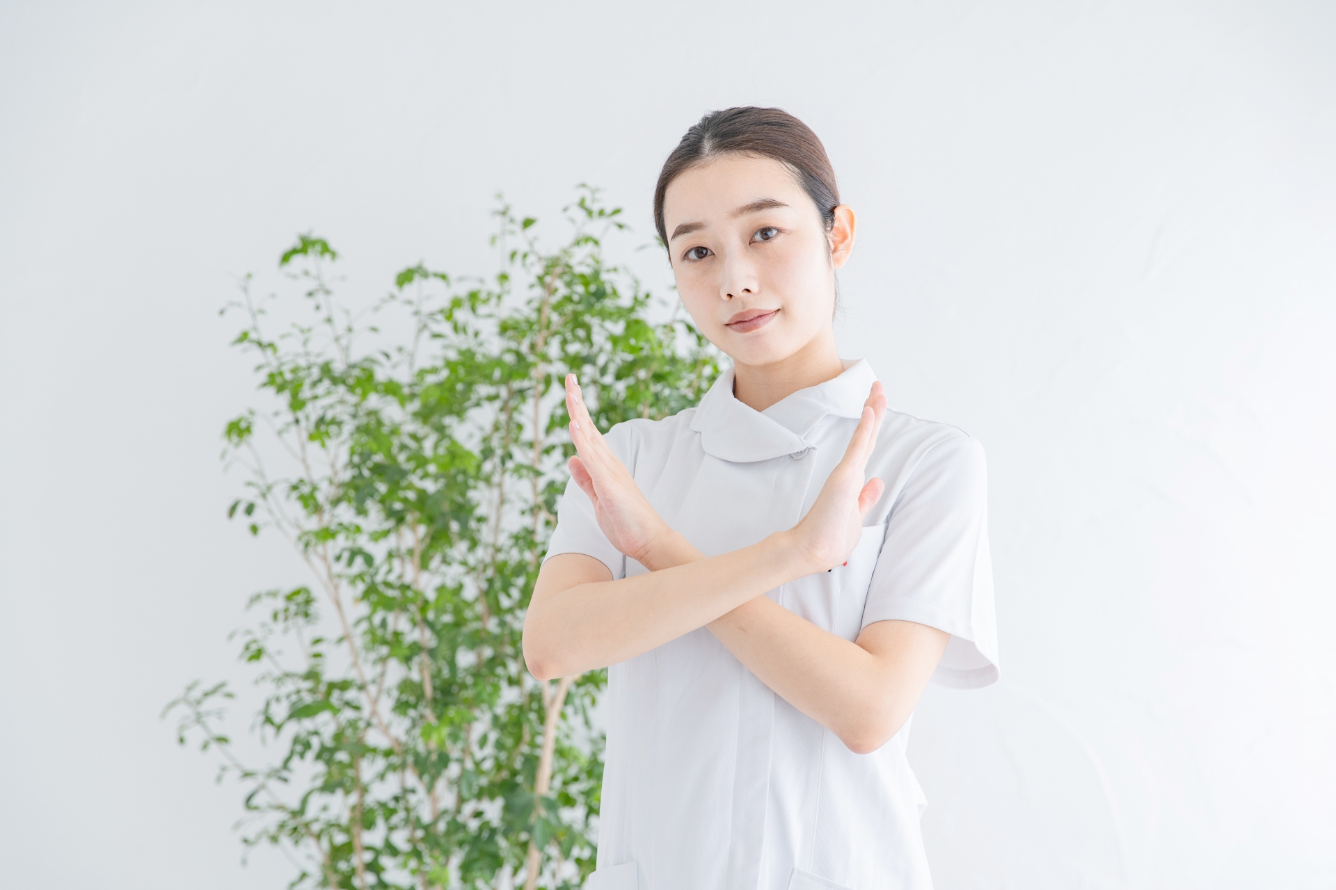 「バツ」のサインをする白衣の女性
