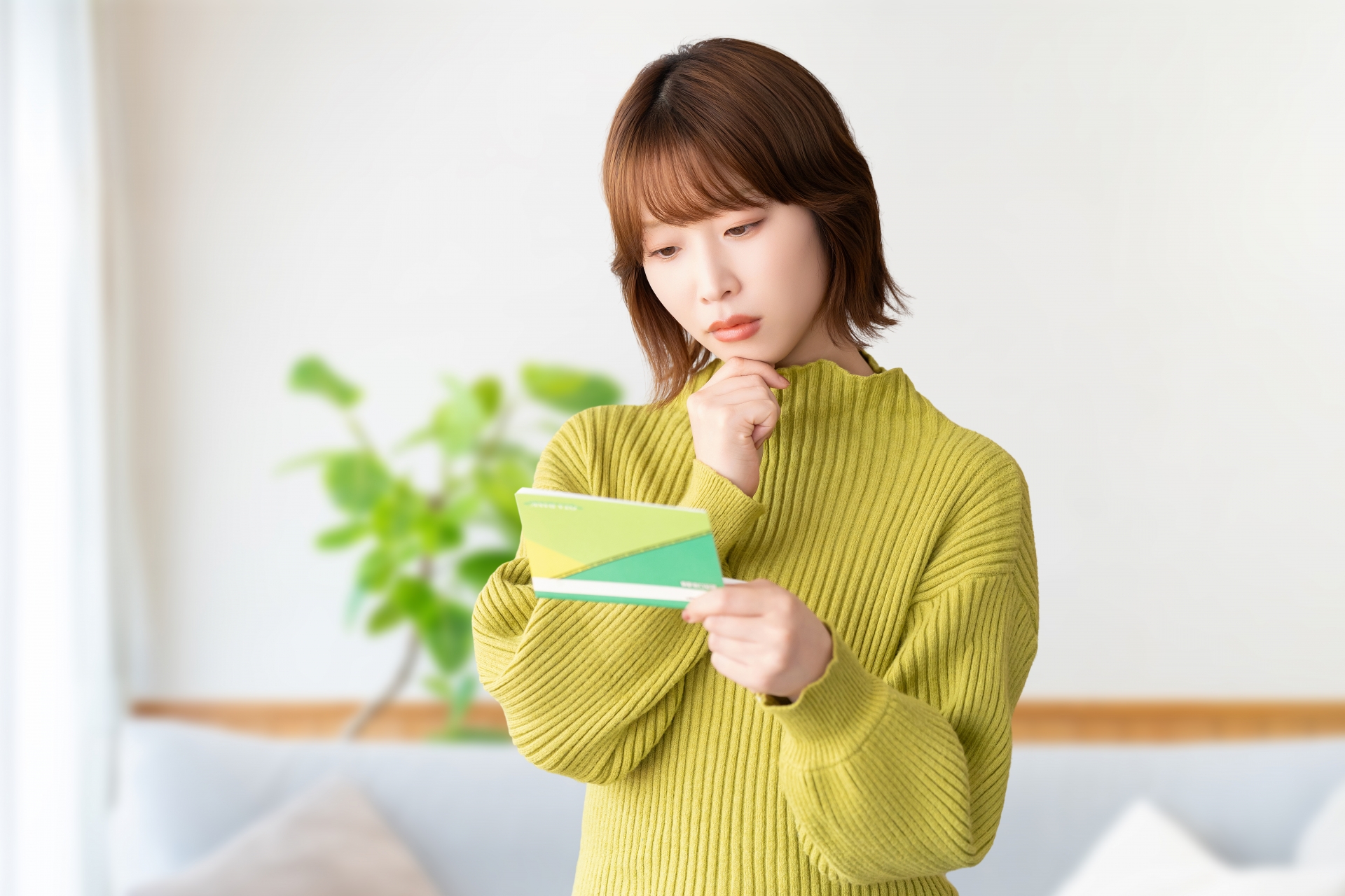 通帳を見て悩む女性