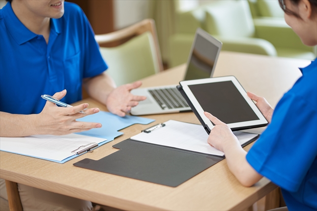 ミーティングをする男女の介護士の手元