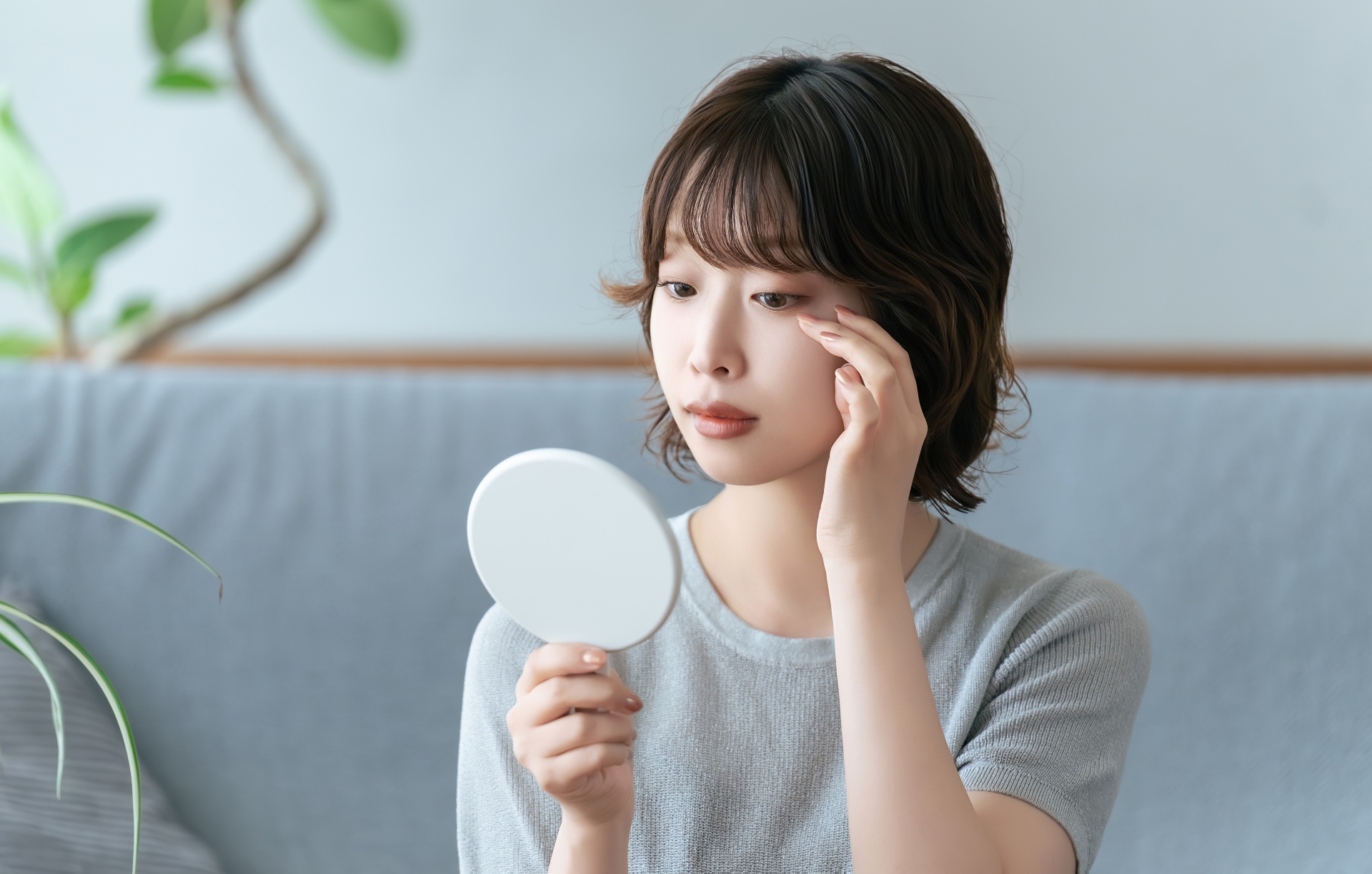 鏡で目元をチェックする女性