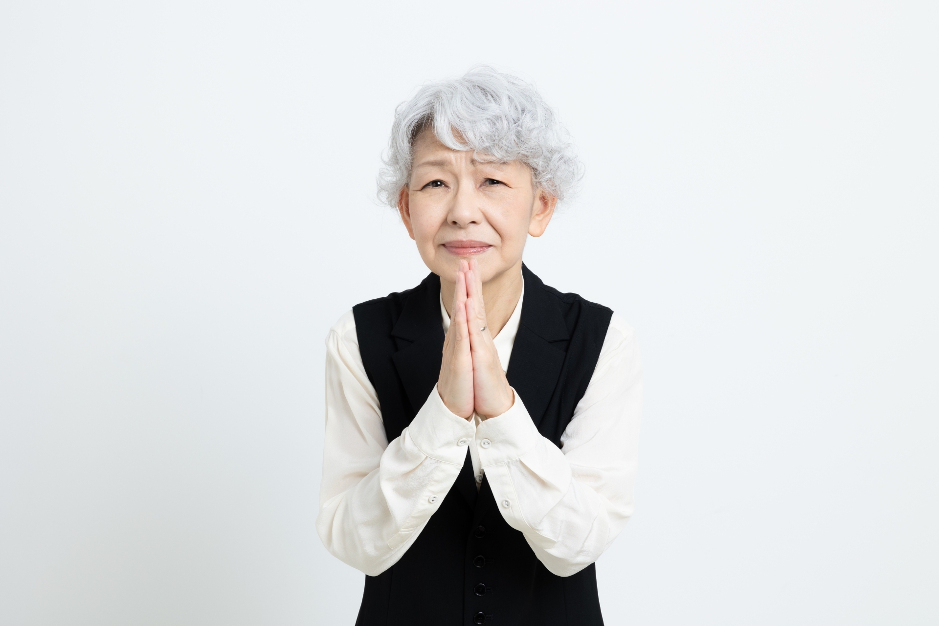 手を合わせてお願いをするシニア女性