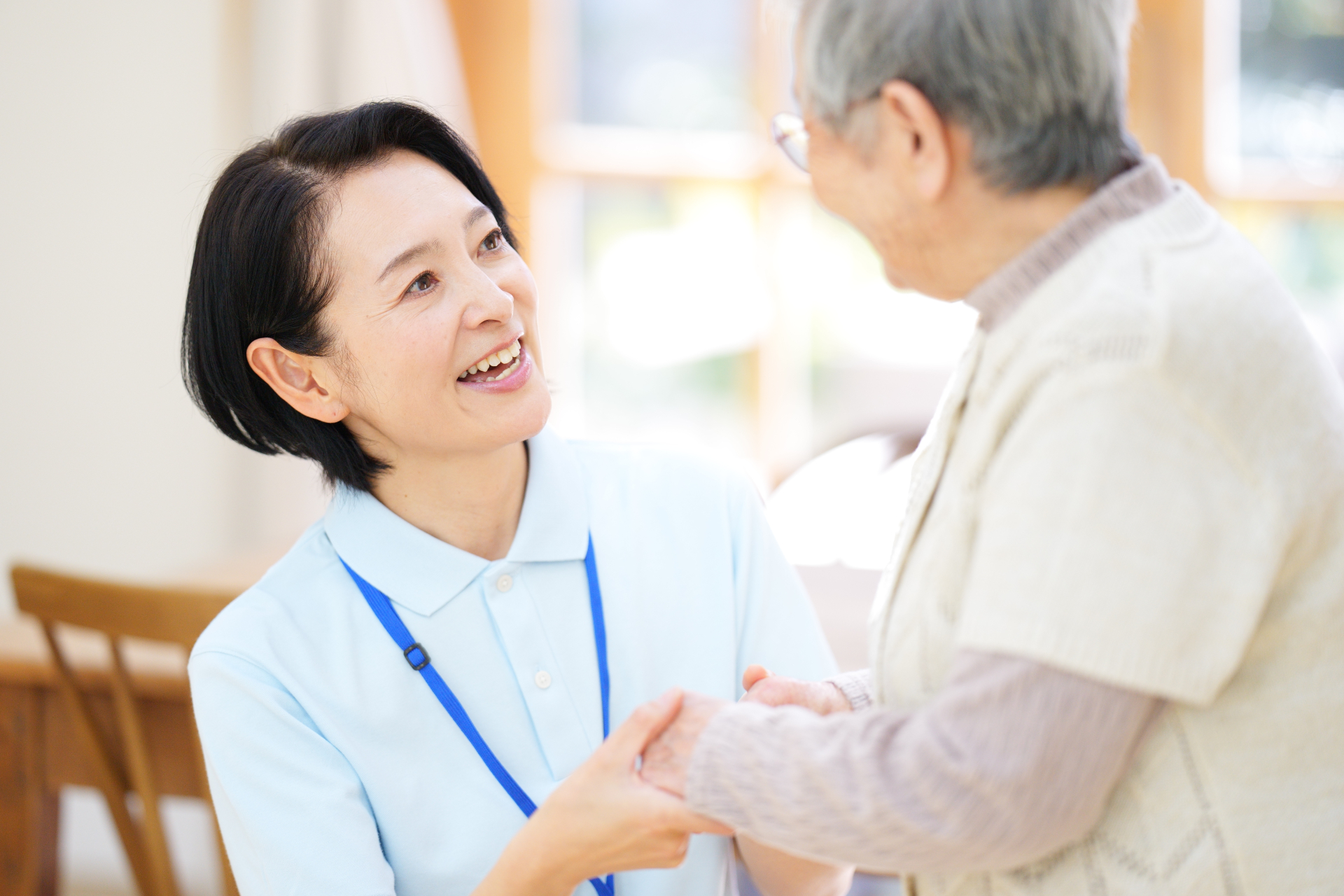 手を握って話している高齢女性と介護士