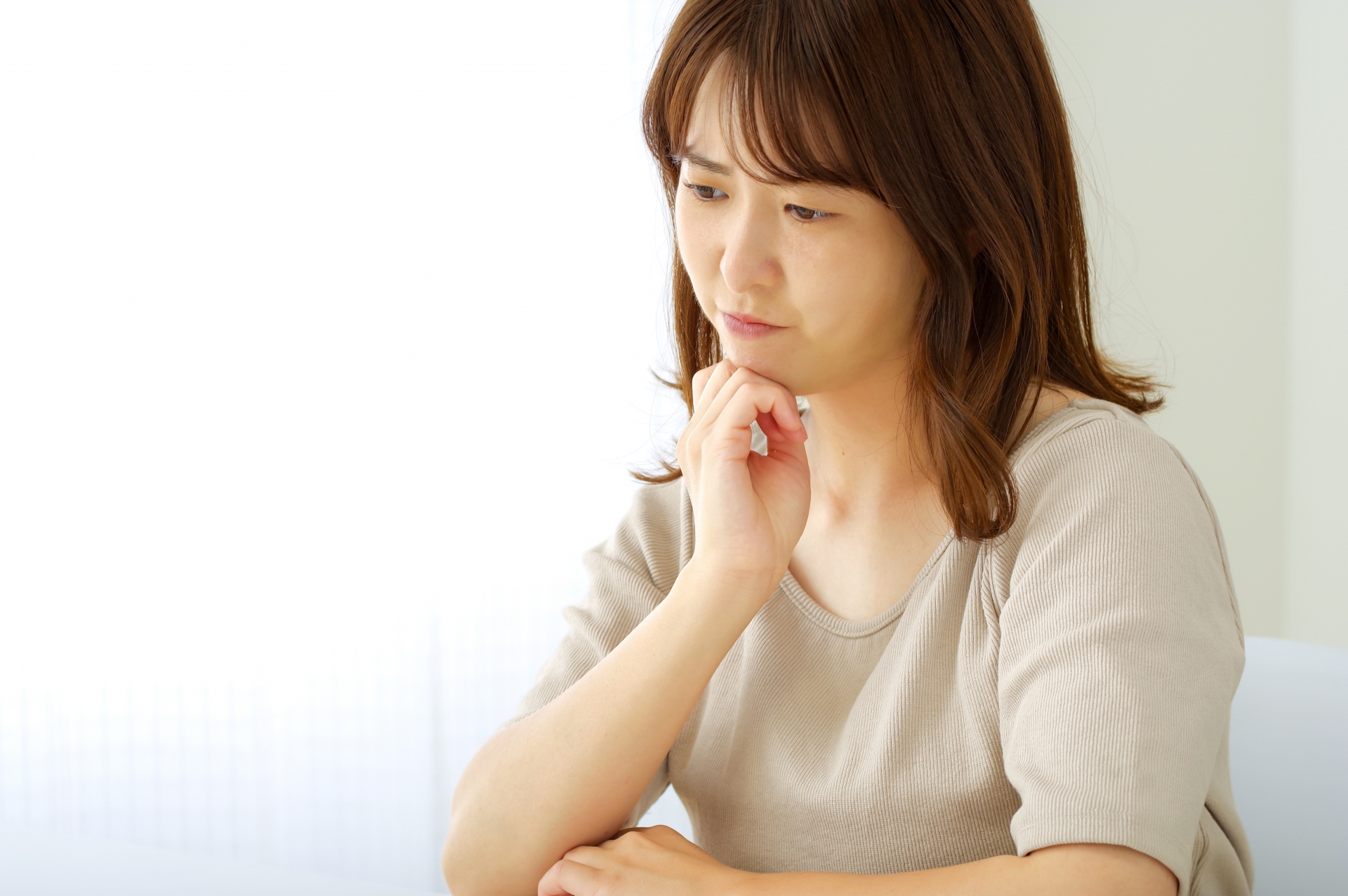 真剣な表情で考え事をする若い女性
