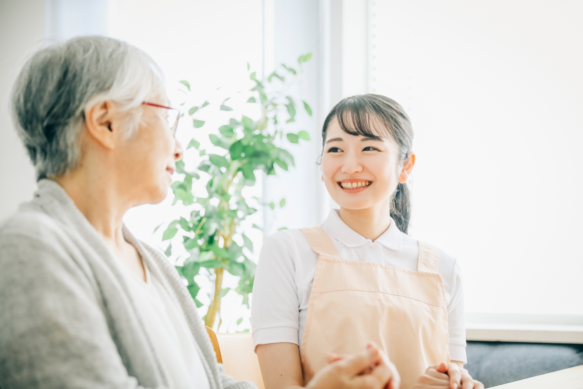 エプロン姿の女性スタッフと高齢者（笑顔）