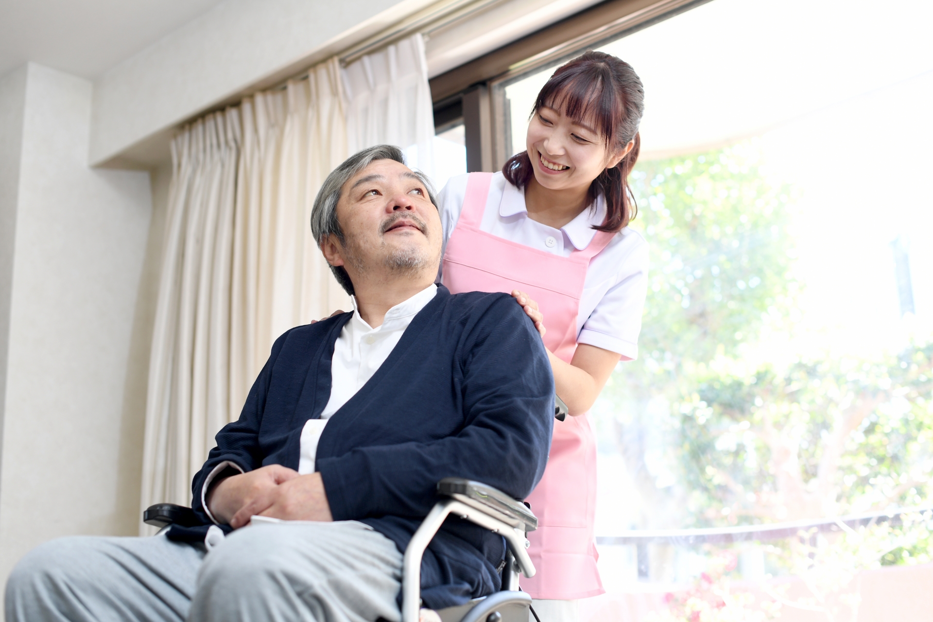 車椅子に乗る高齢者男性と女性の介護士