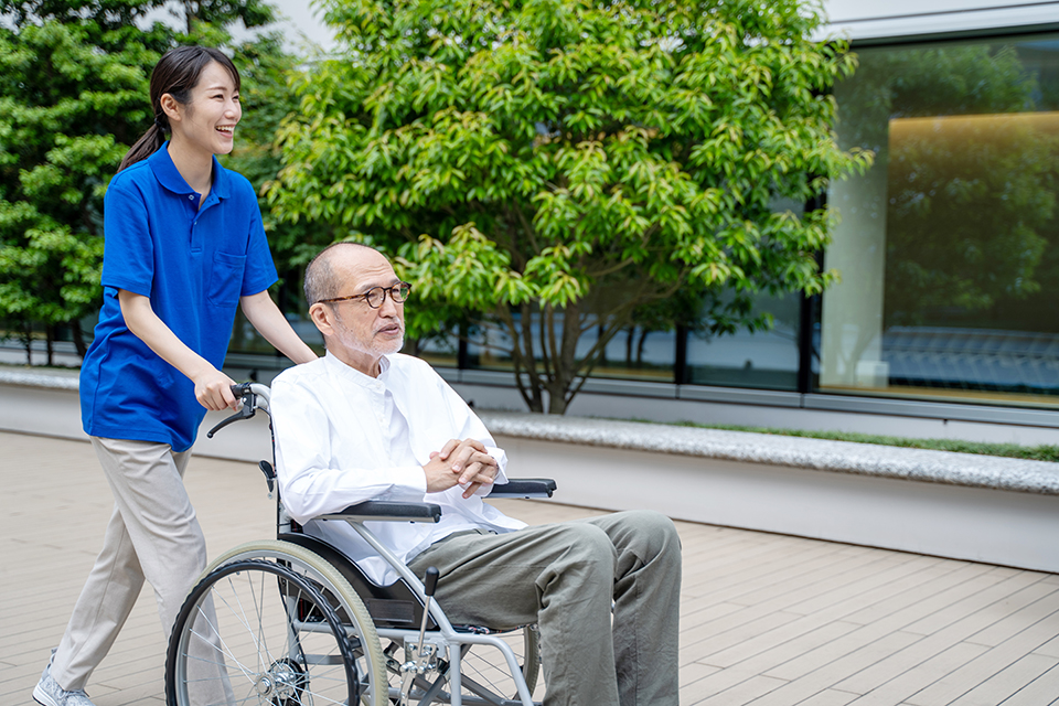 車いすのシニア男性と介護施設スタッフ