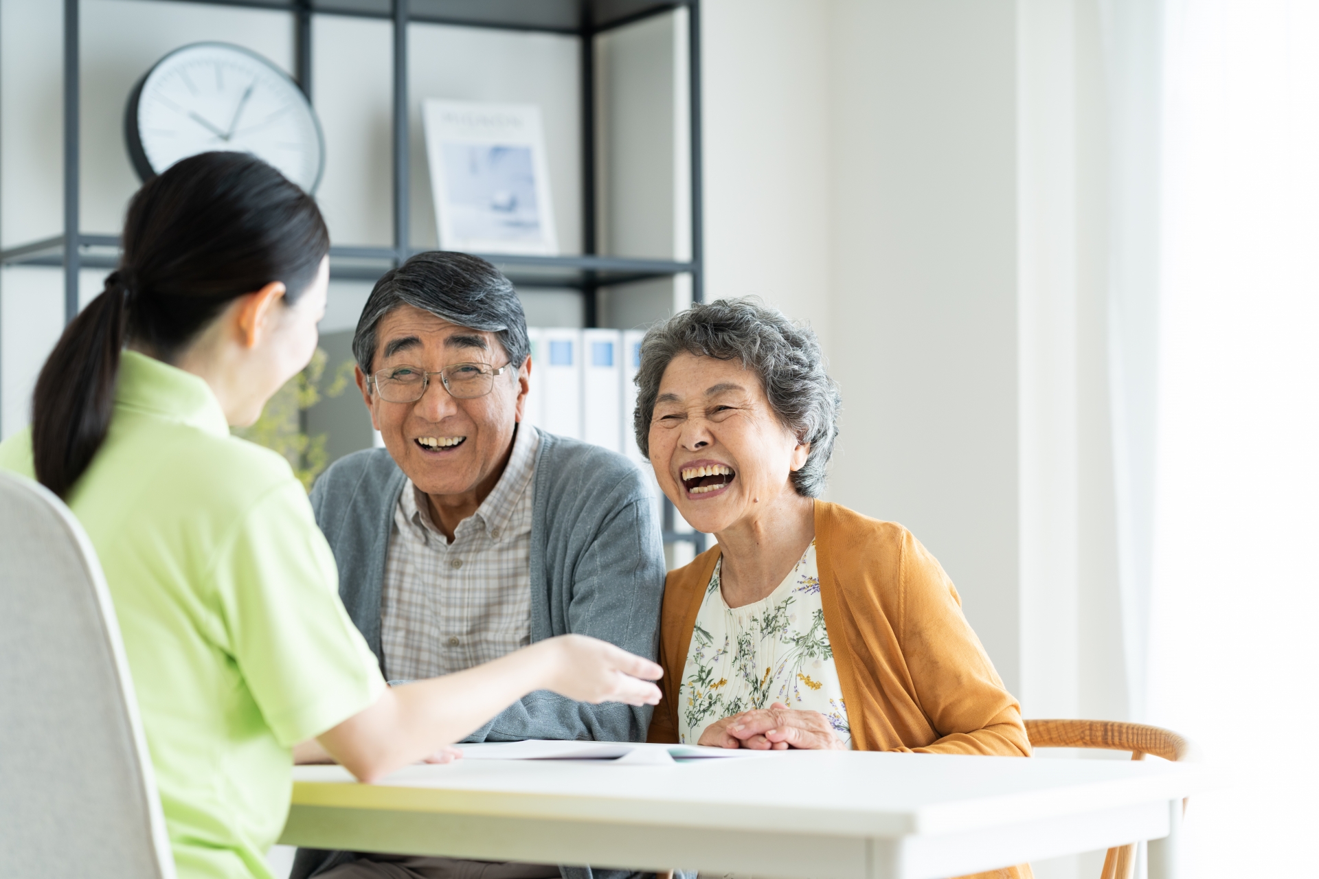 笑う高齢夫婦と対応する介護士