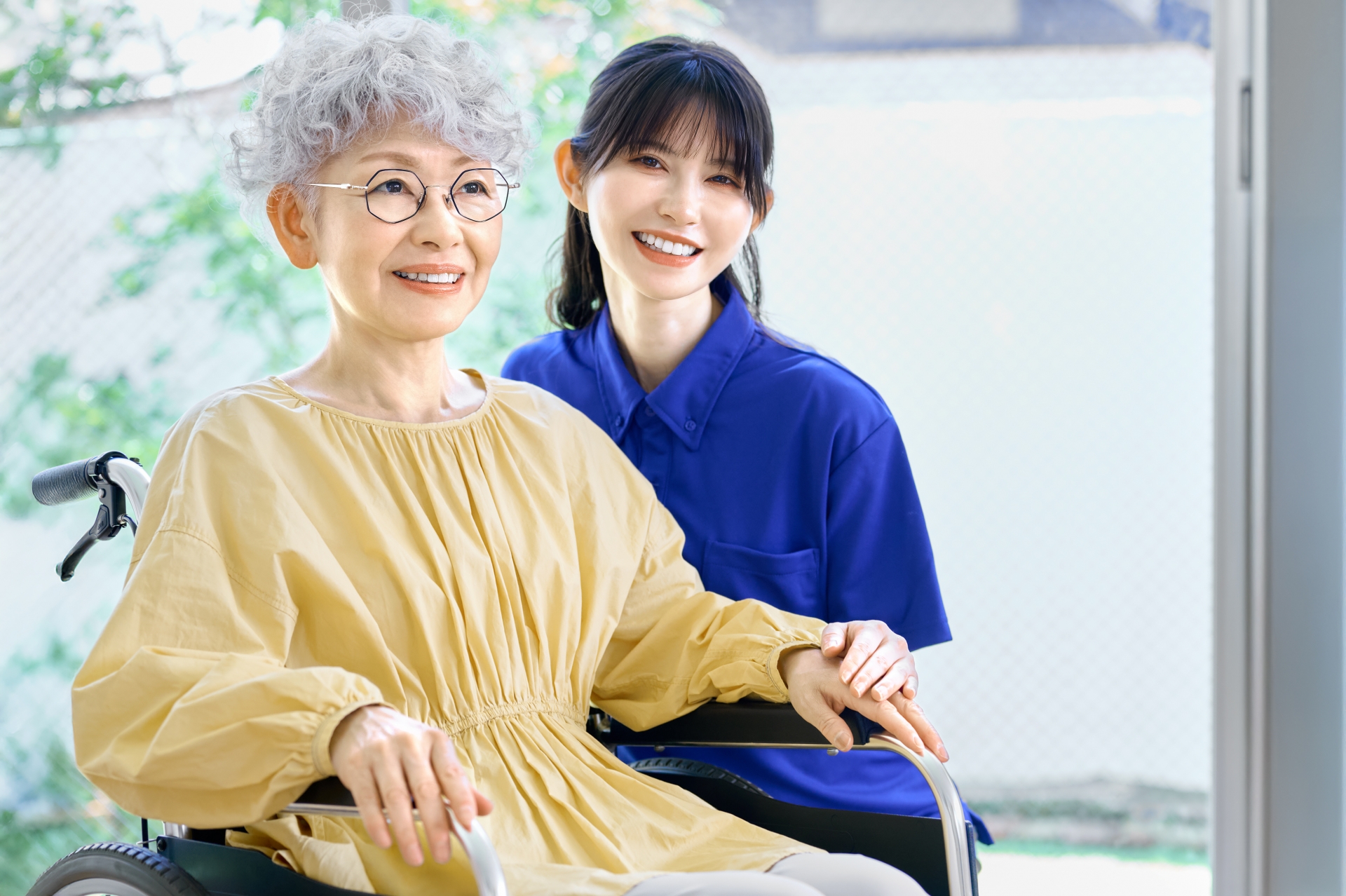 車椅子の女性に寄り添う介護士
