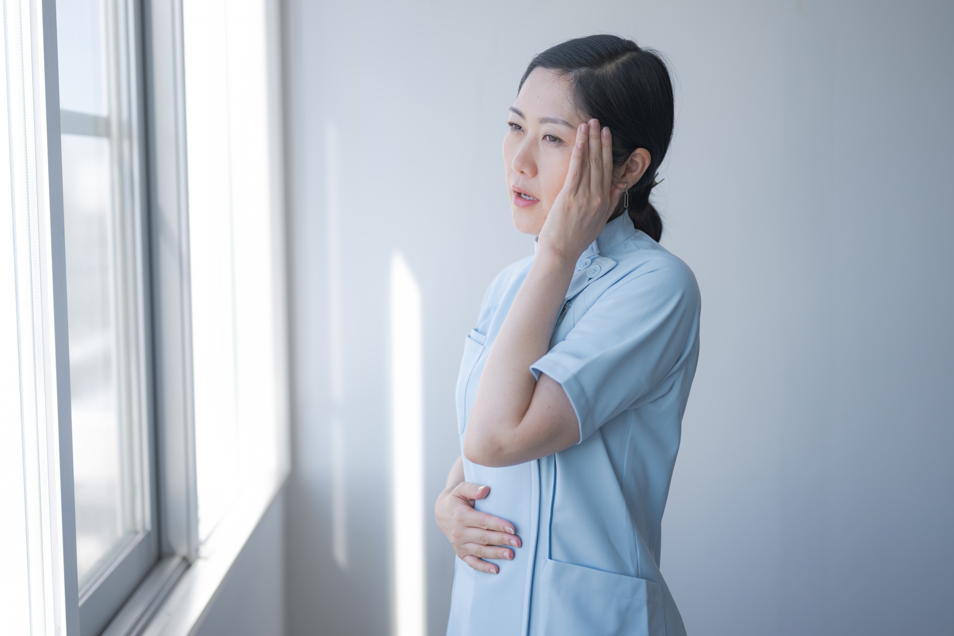 頭を押さえるメディカル女性