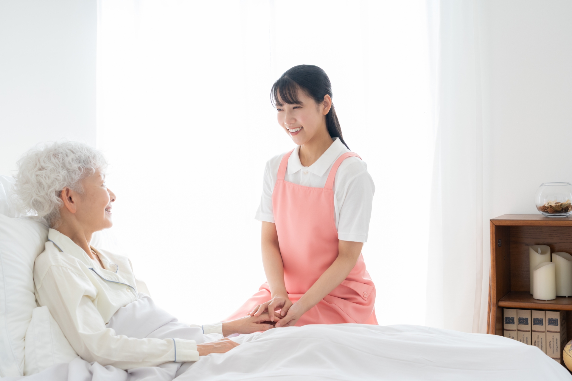 寝ているシニア女性を介護をする介護士