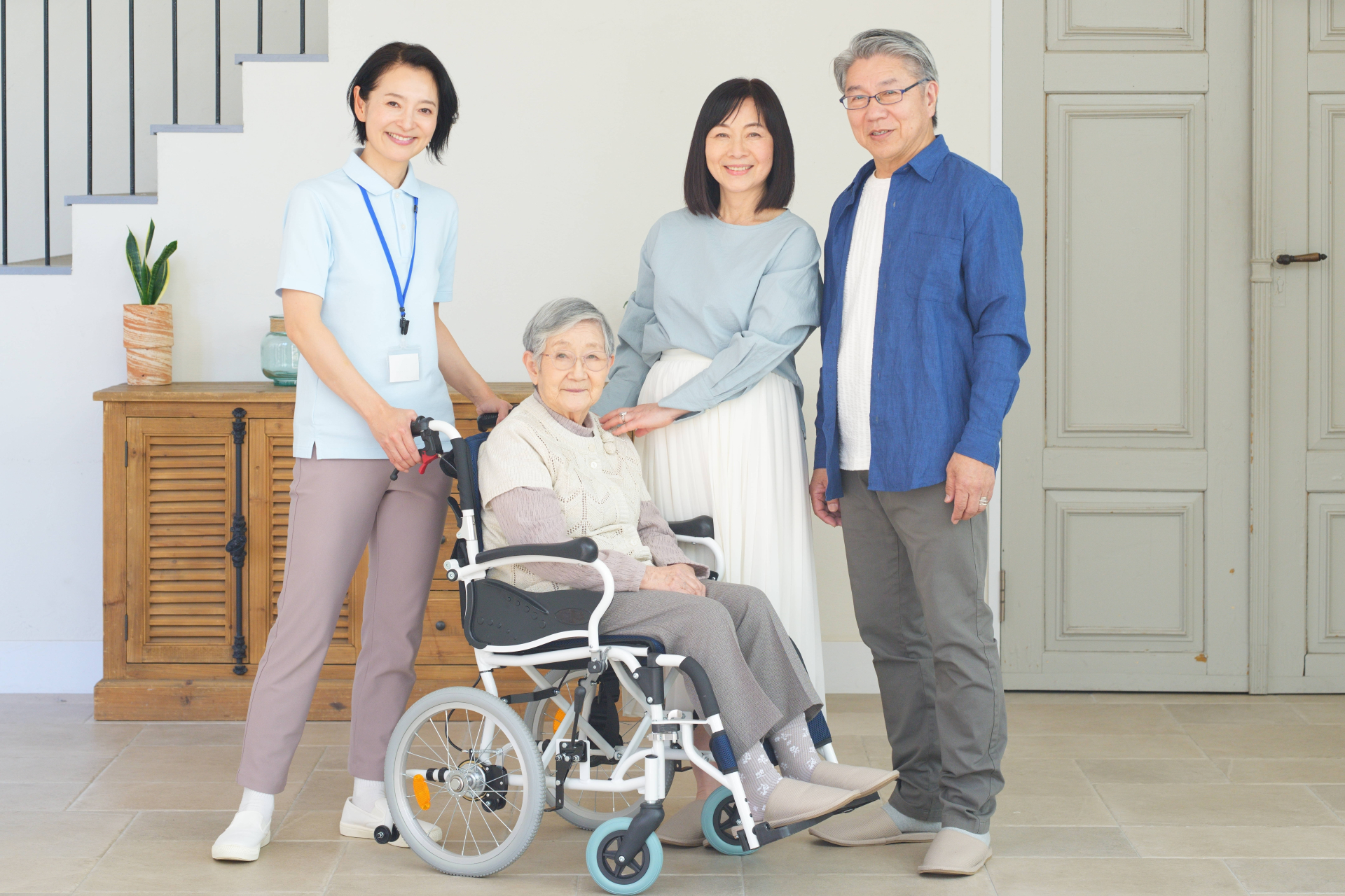 車椅子に座る高齢女性と家族と介護士