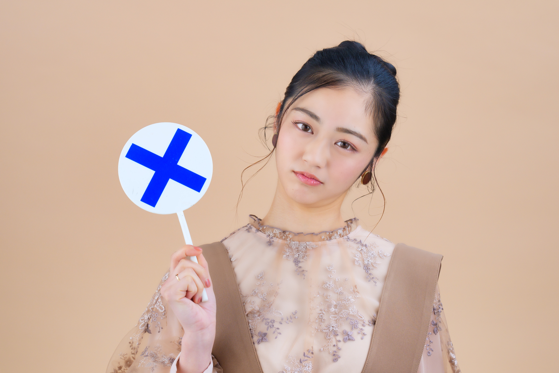 ✕マークを持った女性