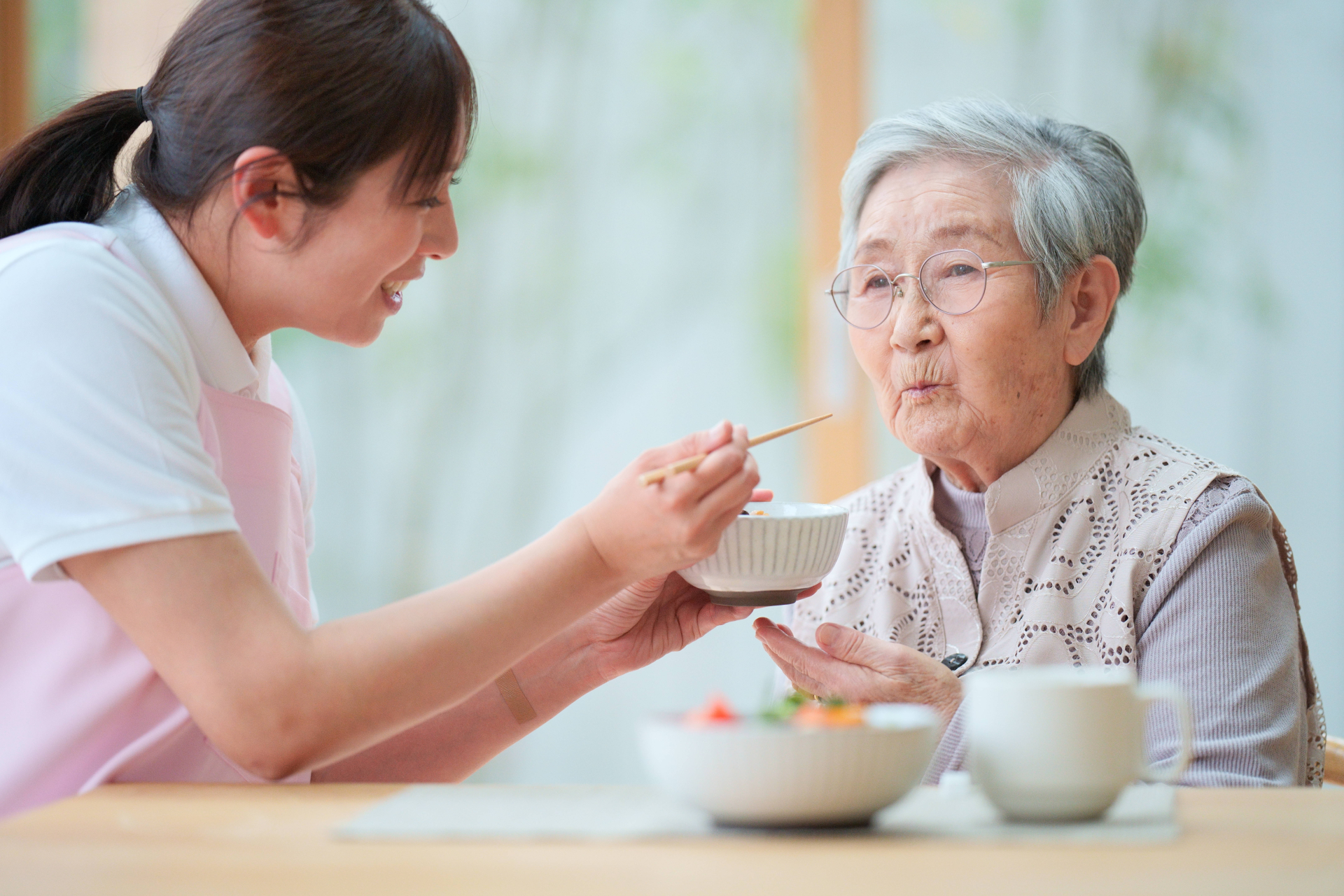 高齢女性の食事介助をする女性