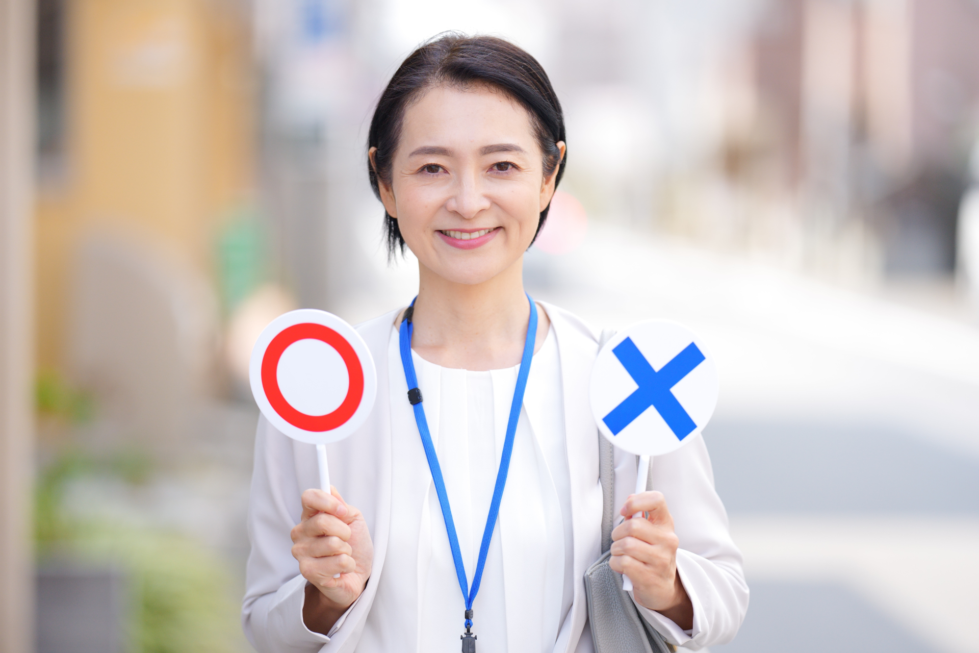 屋外でマルバツの札を見せるケアマネジャー