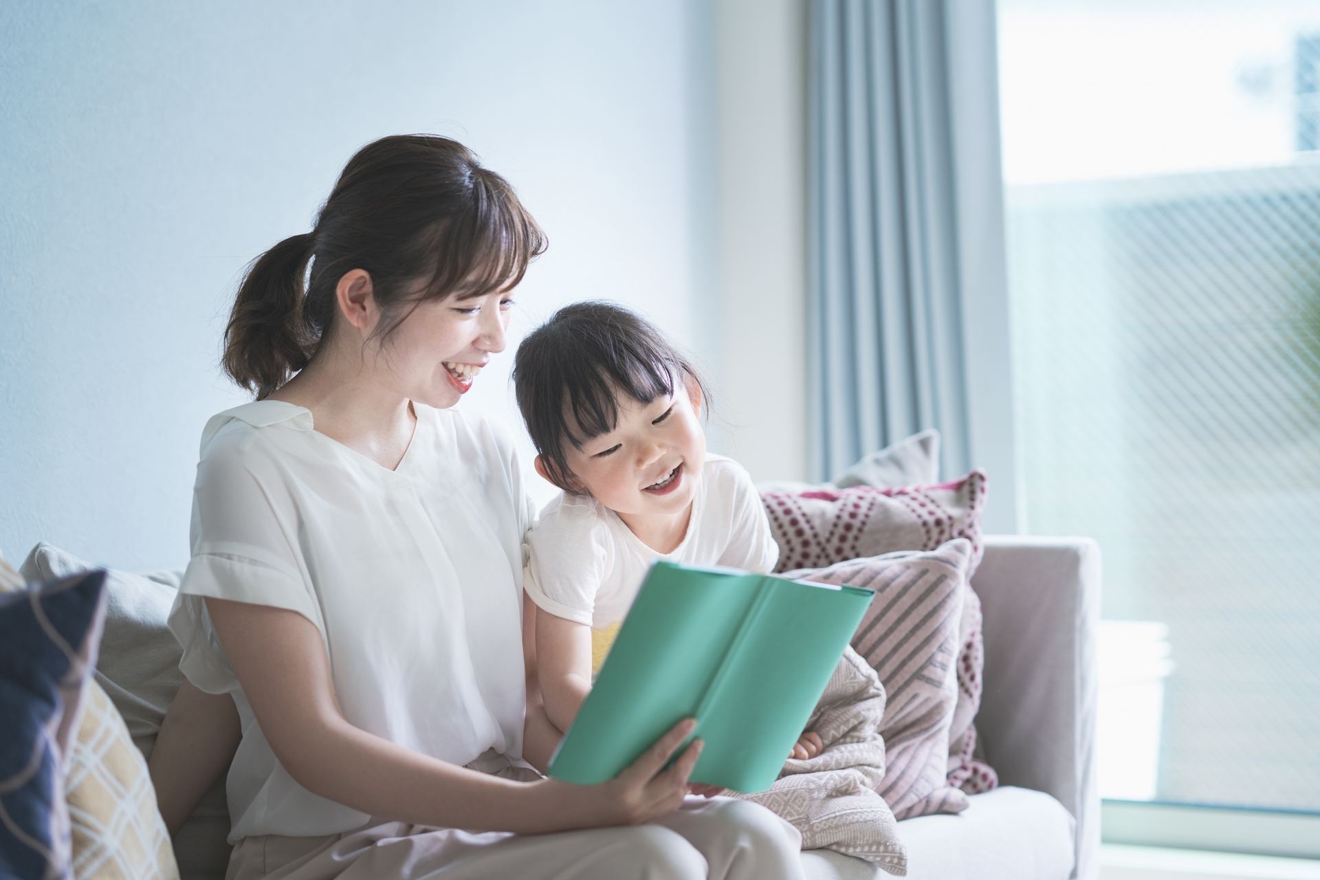 ソファに座って絵本を読む親子