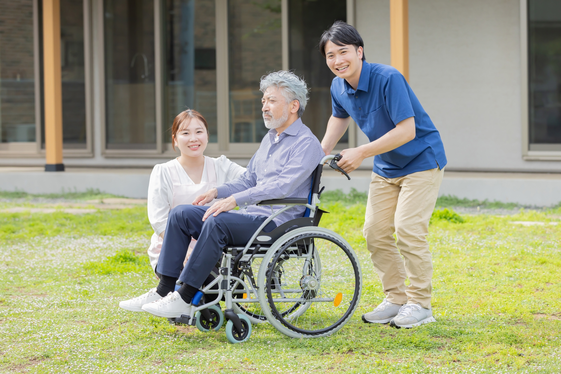 車椅子に乗ったシニア男性とへルパー
