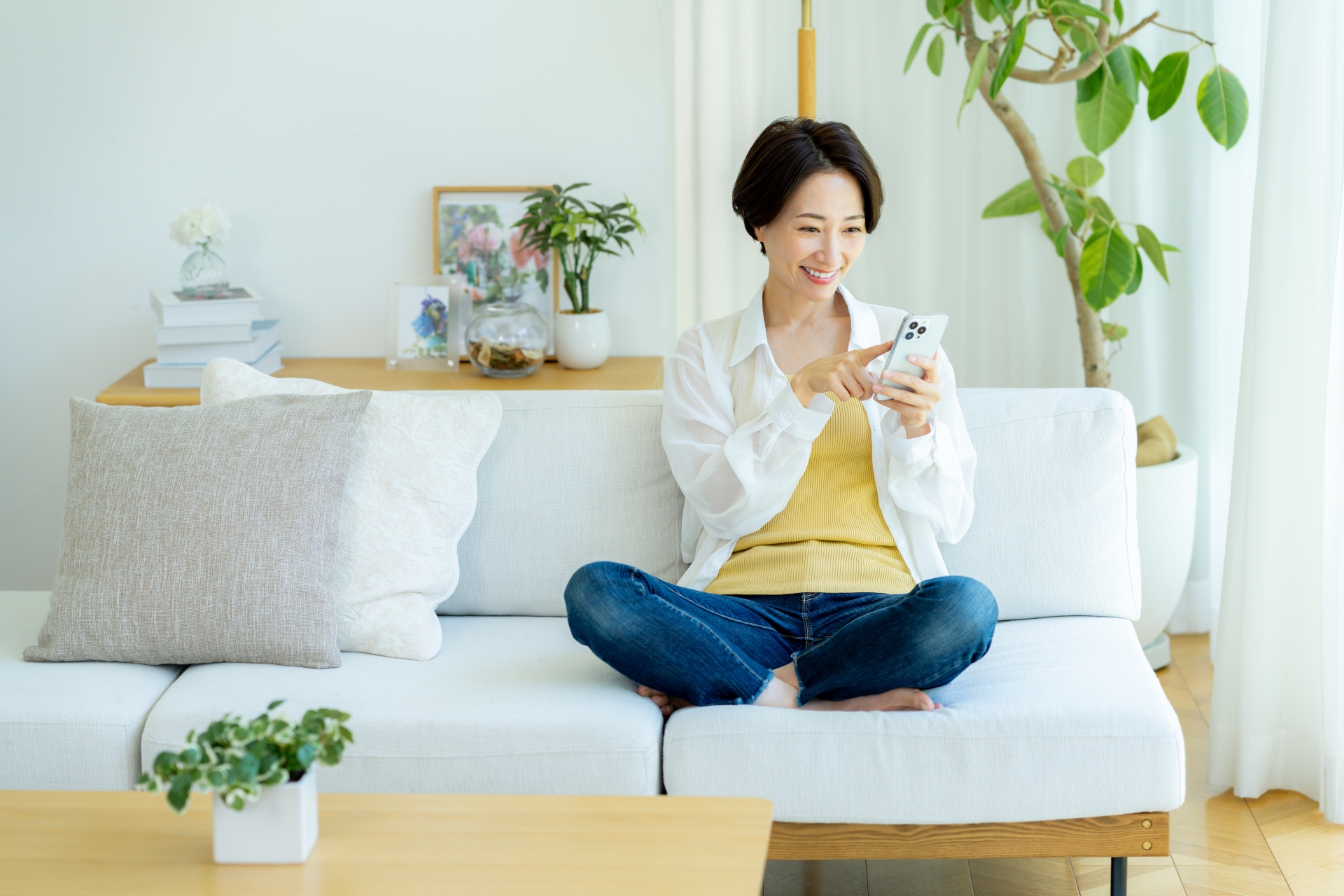 部屋でスマホを使うミドル女性