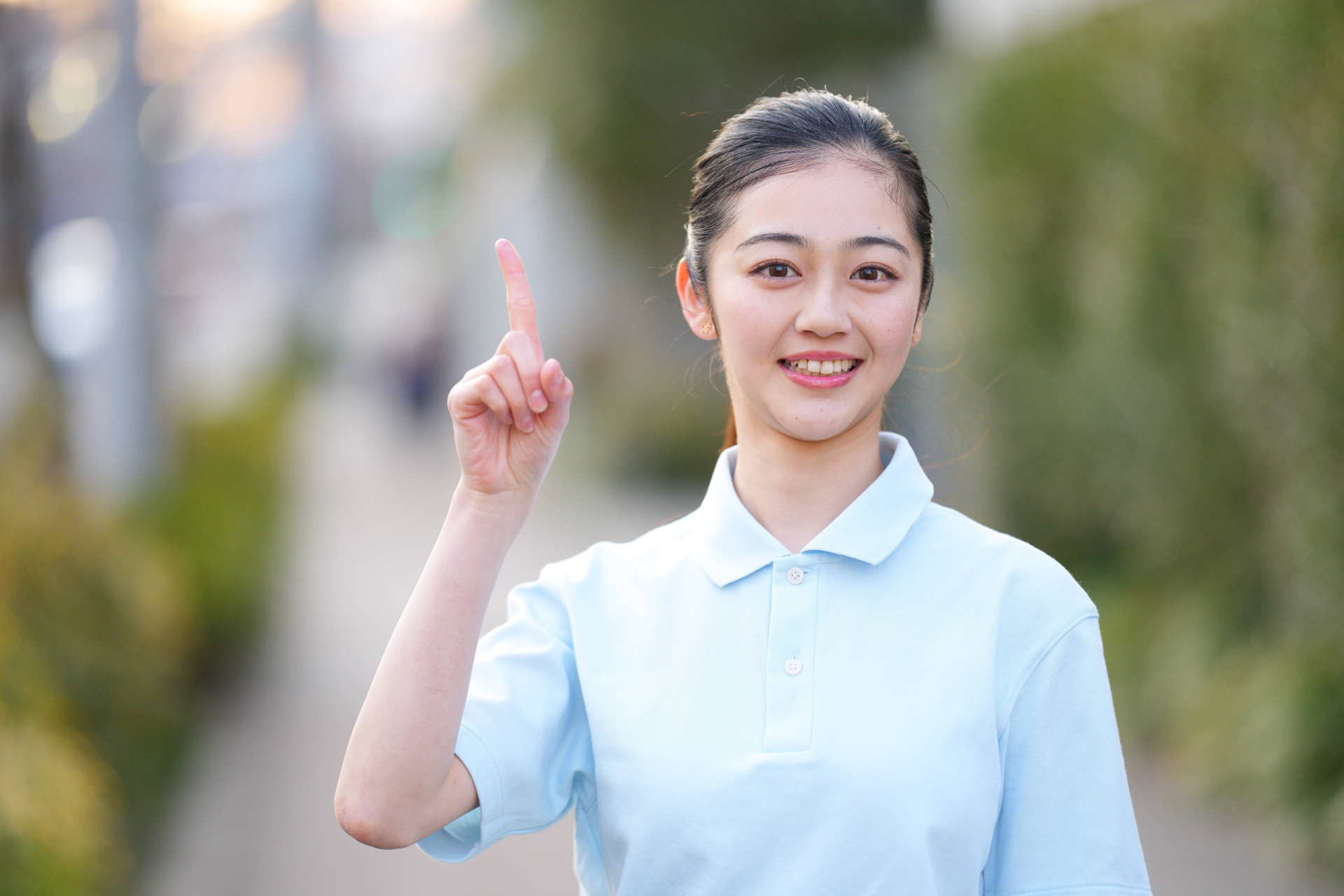 屋外で人差し指を立てる若い女性介護士