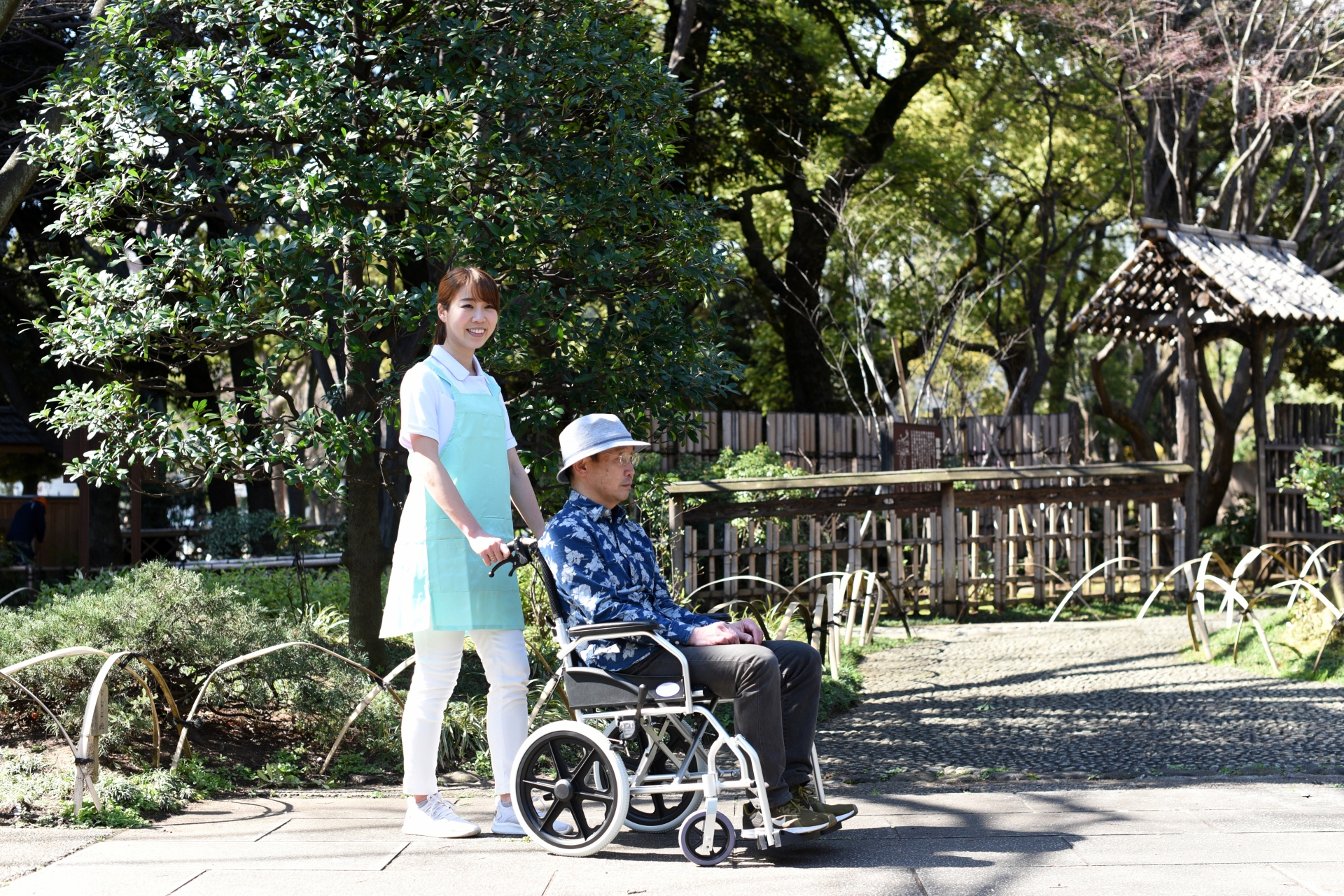 車椅子を押す介護士の女性とシニア男性
