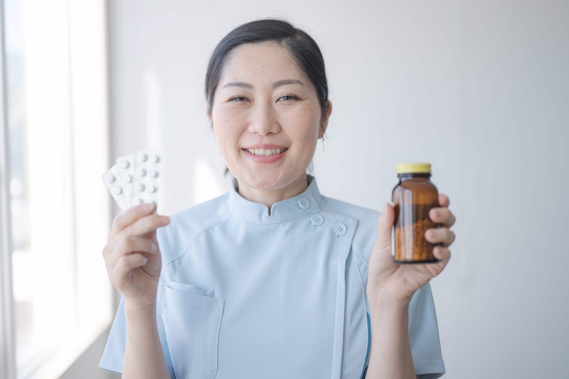 薬を両手にもつ薬剤師
